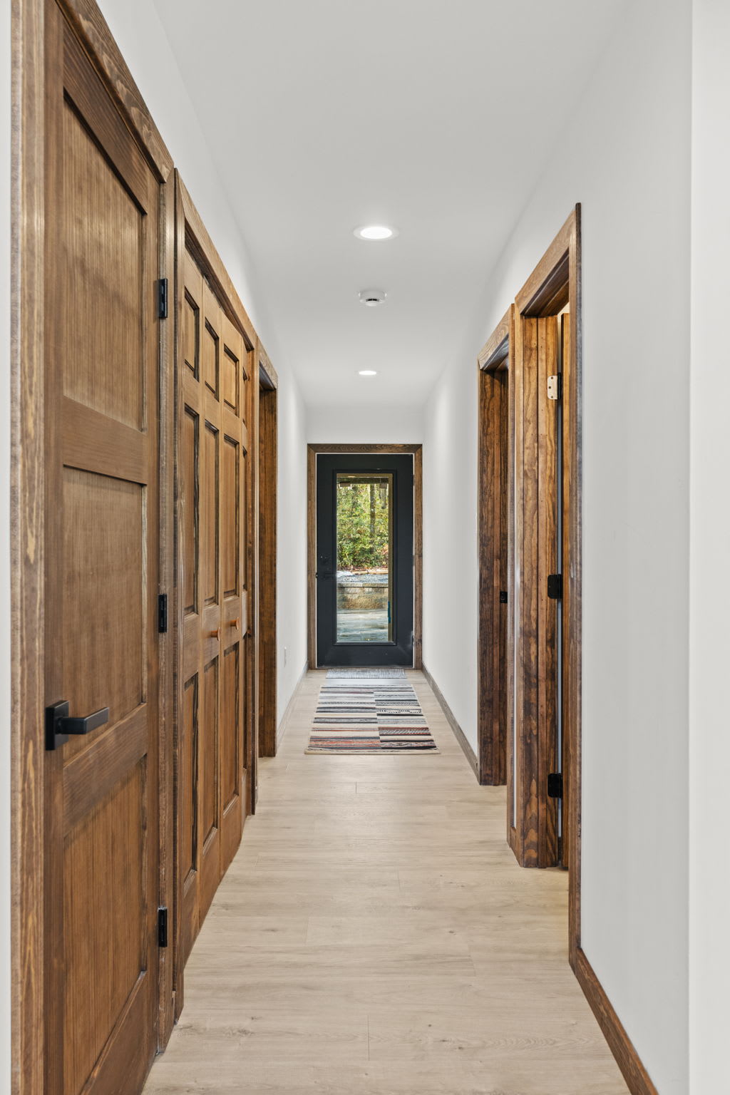 Bright hallway with warm wood paneling leads to bedrooms and baths.