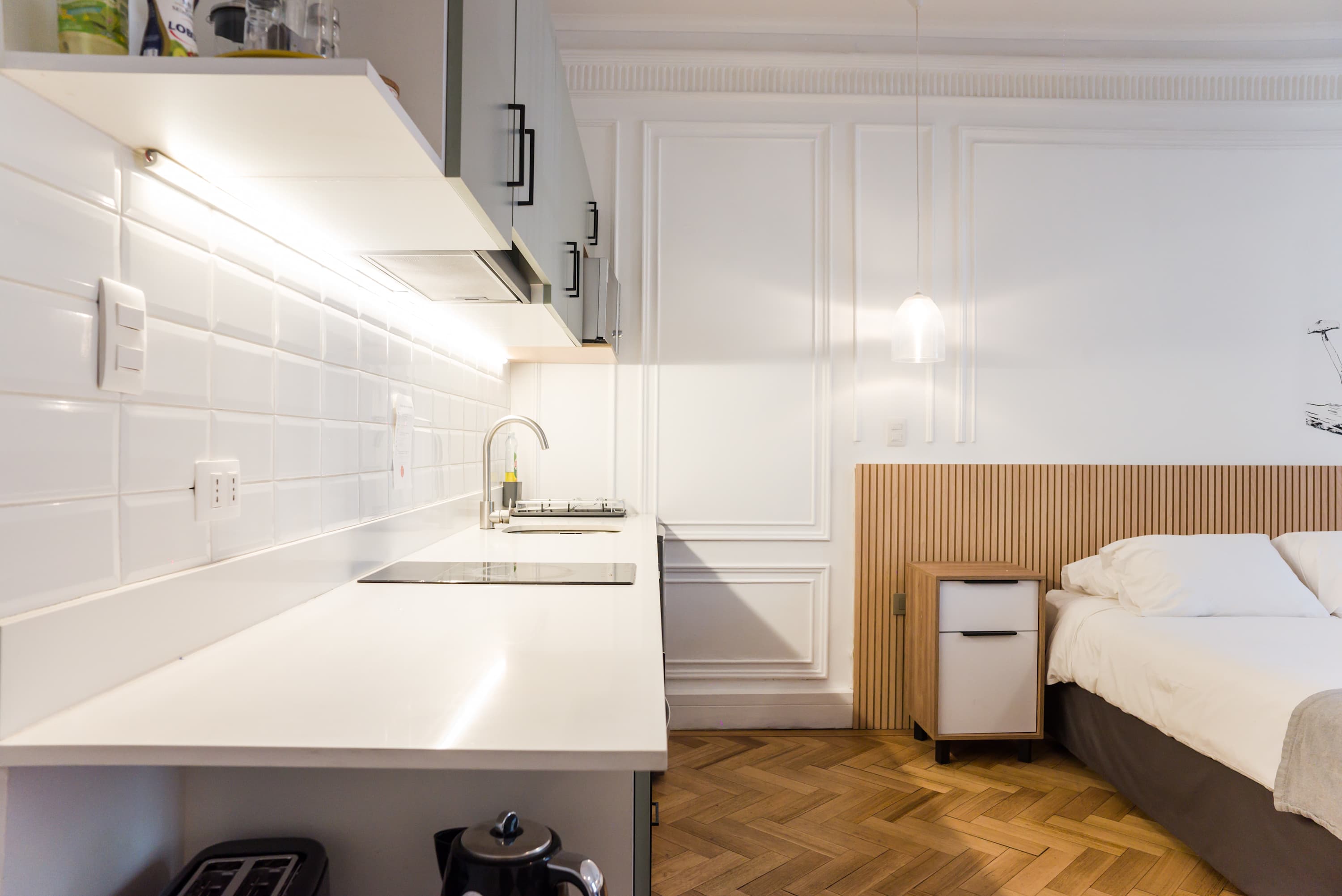 Sleek studio kitchen with modern amenities and cozy sleeping area, perfect for a stylish stay in the heart of the city.