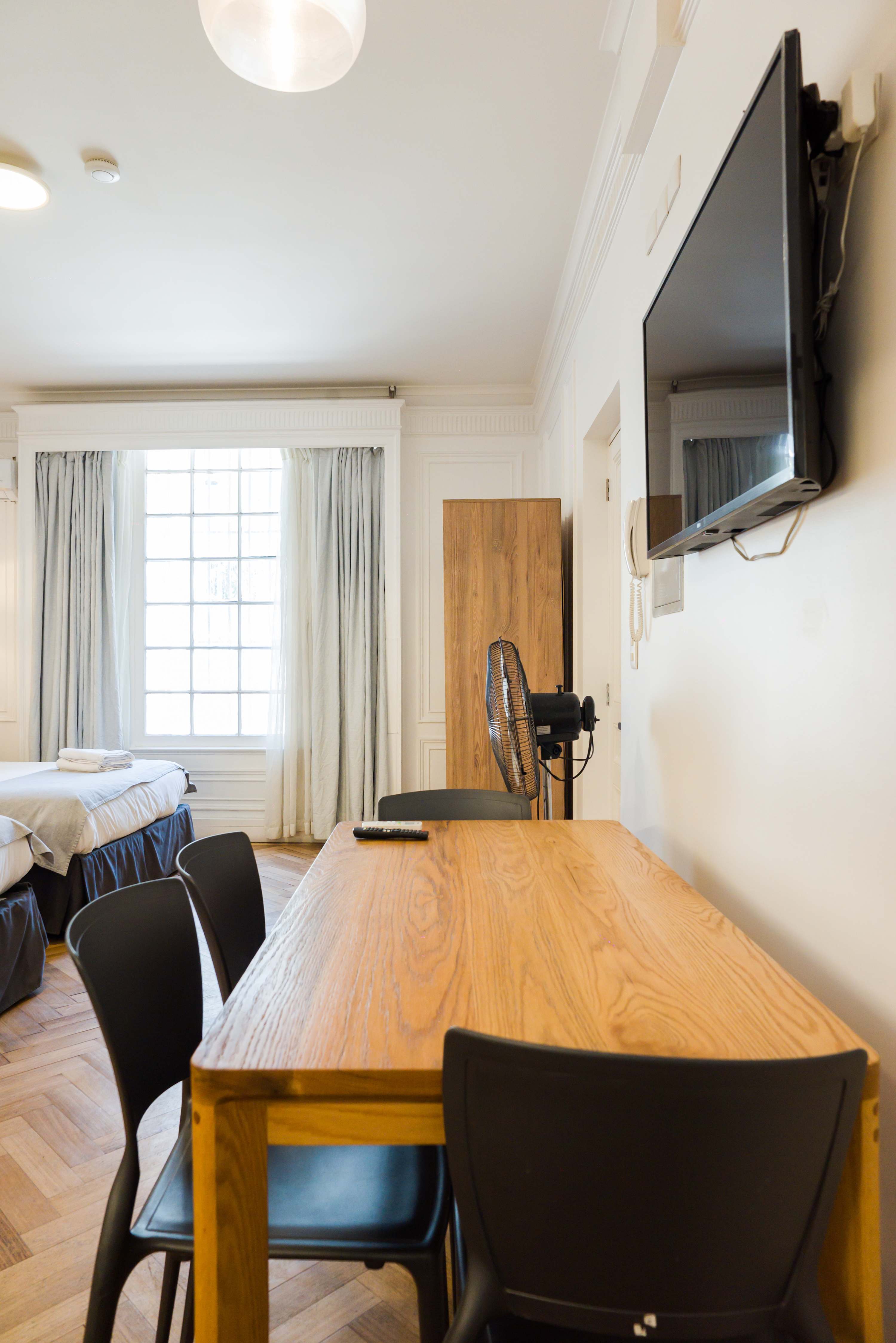 Cozy studio with ample natural light, featuring a dining area and modern amenities for a comfortable stay.