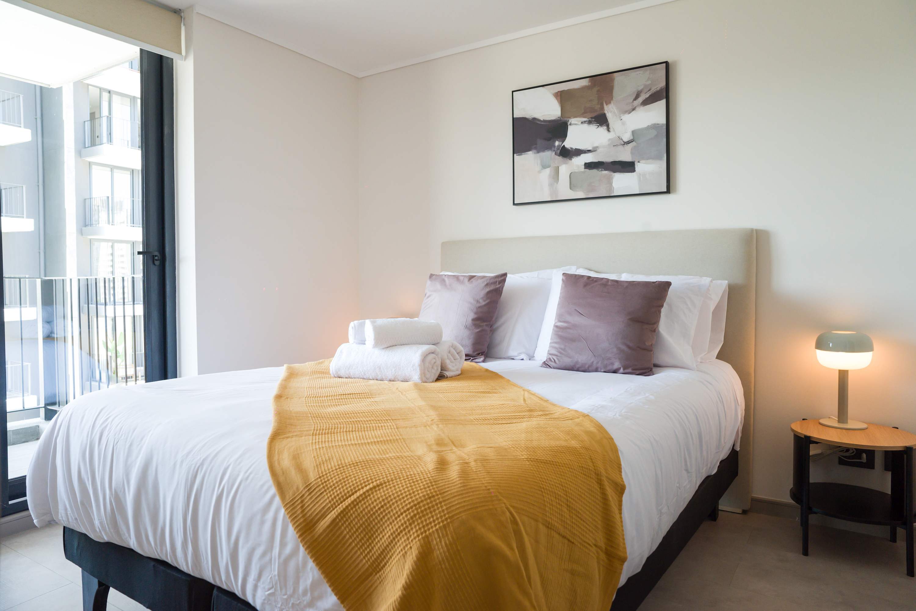 Relax in this cozy bedroom with modern decor and enjoy a stunning city view from the large window.