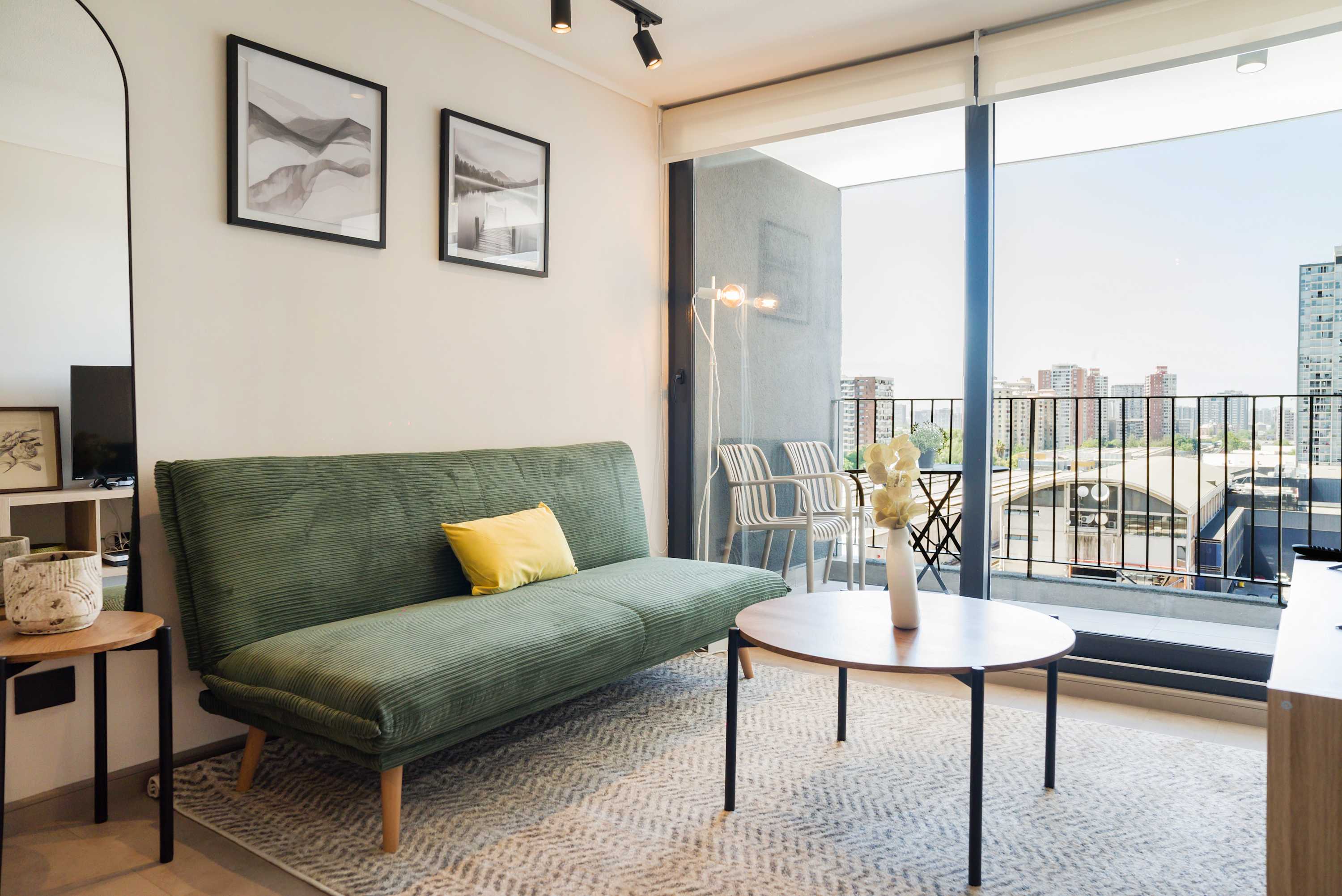 Bright and cozy living area with a green sofa and city-view balcony, perfect for relaxation.
