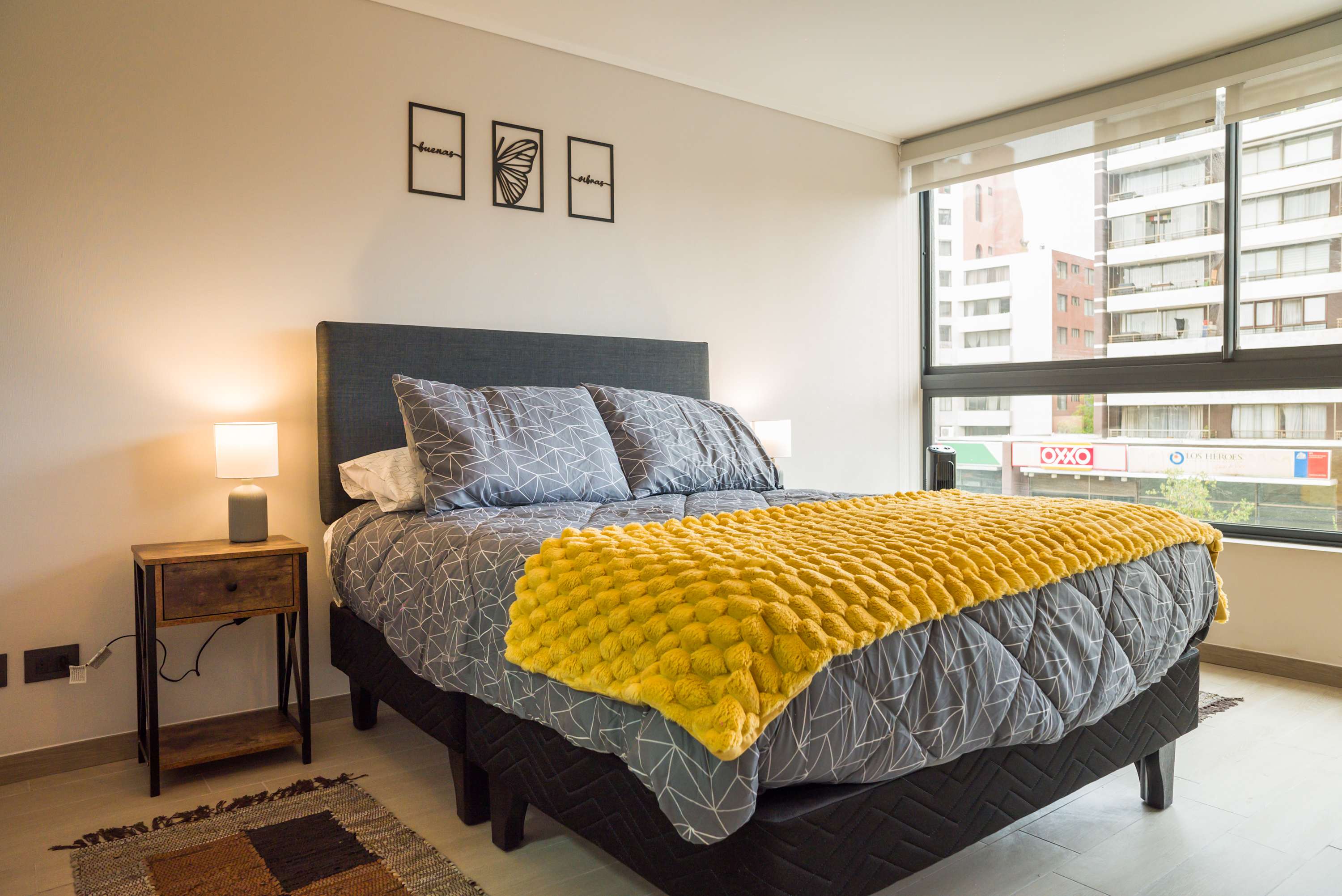 Unwind in this chic bedroom with city views, featuring a cozy bed and vibrant decor for a perfect retreat.