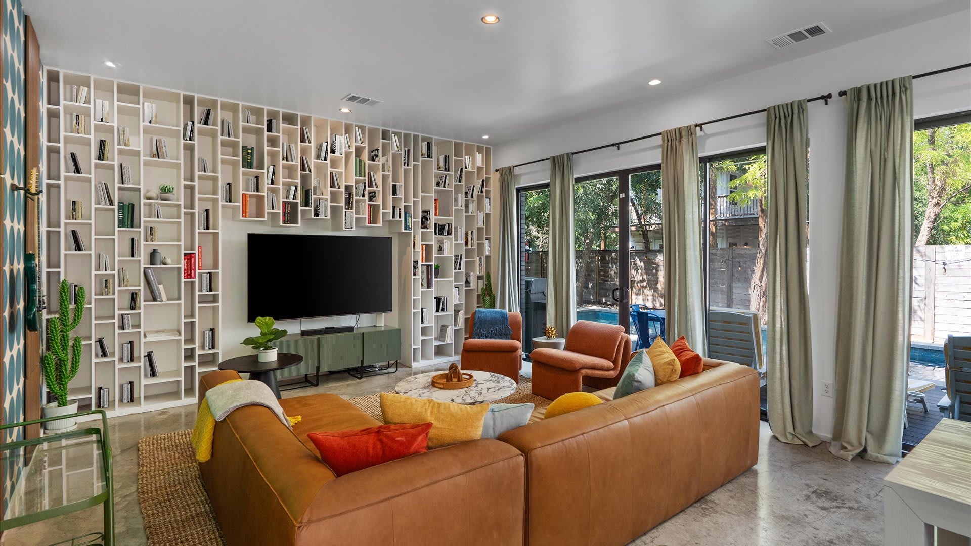 Bright & Stylish Living Area - A sun-filled living room with comfortable seating, a smart TV, modern décor, and large windows.