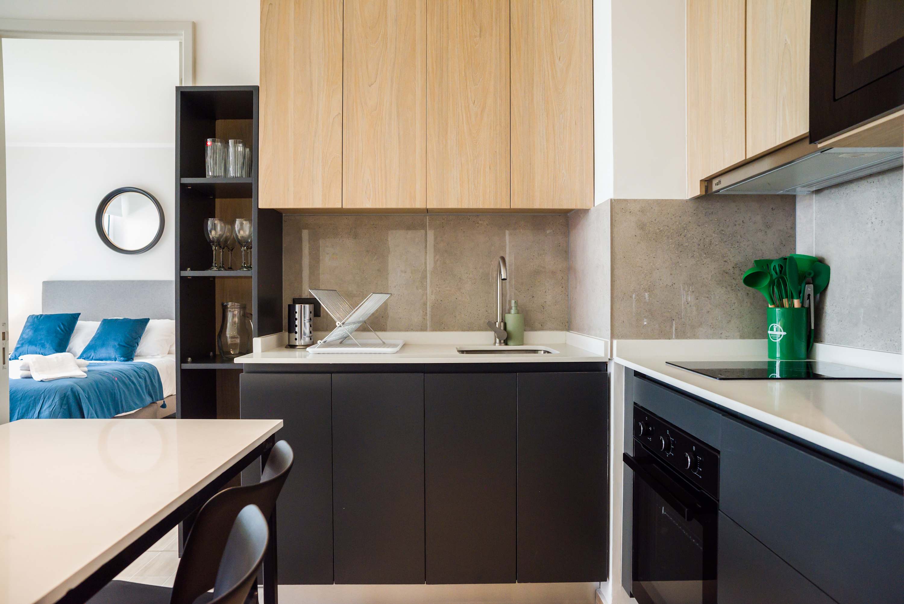 Modern kitchen with stylish cabinetry and a glimpse into a cozy bedroom, perfect for a seamless living experience.