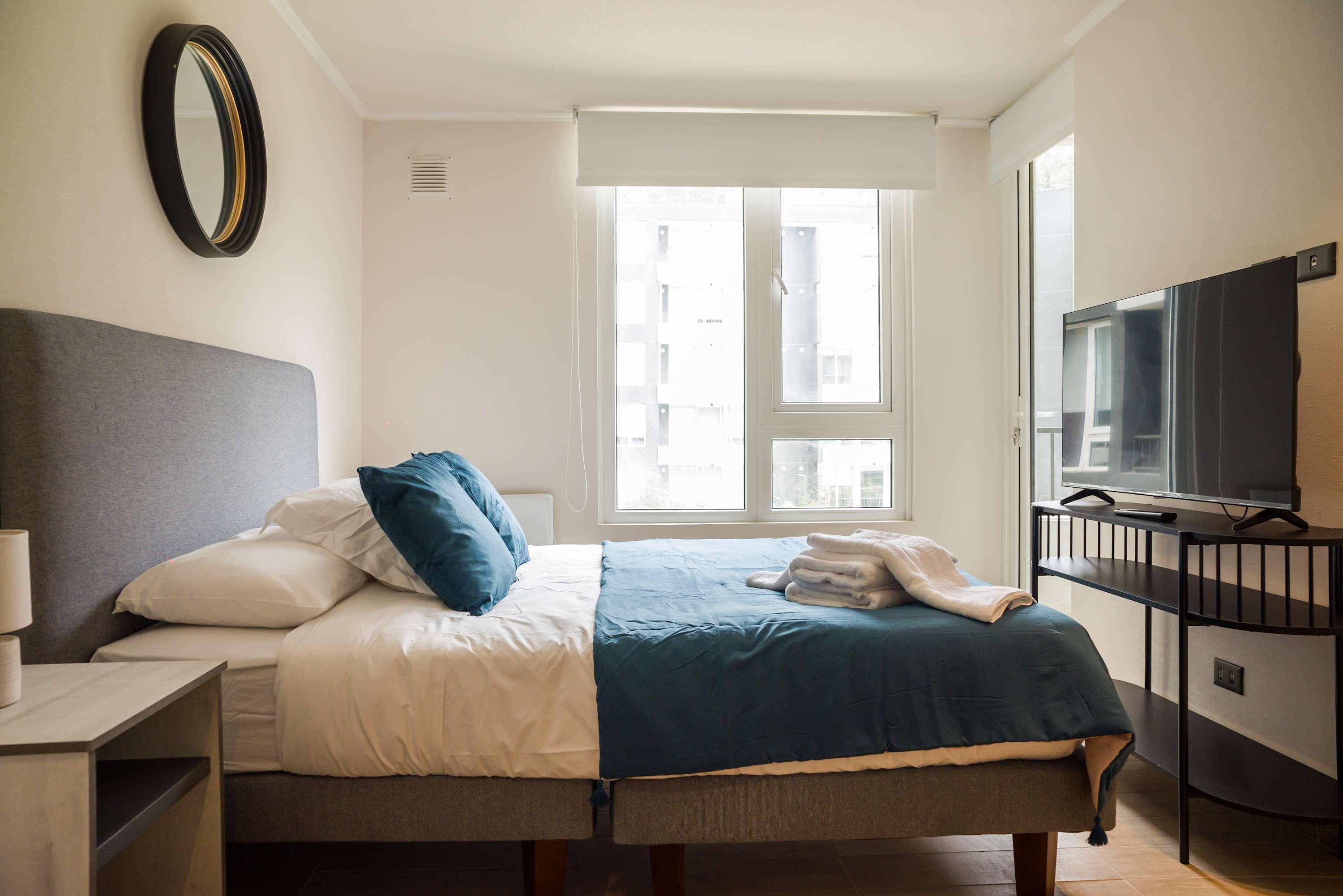 Relax in this bright and modern bedroom with a comfy bed and natural light, perfect for unwinding after a day of exploring.