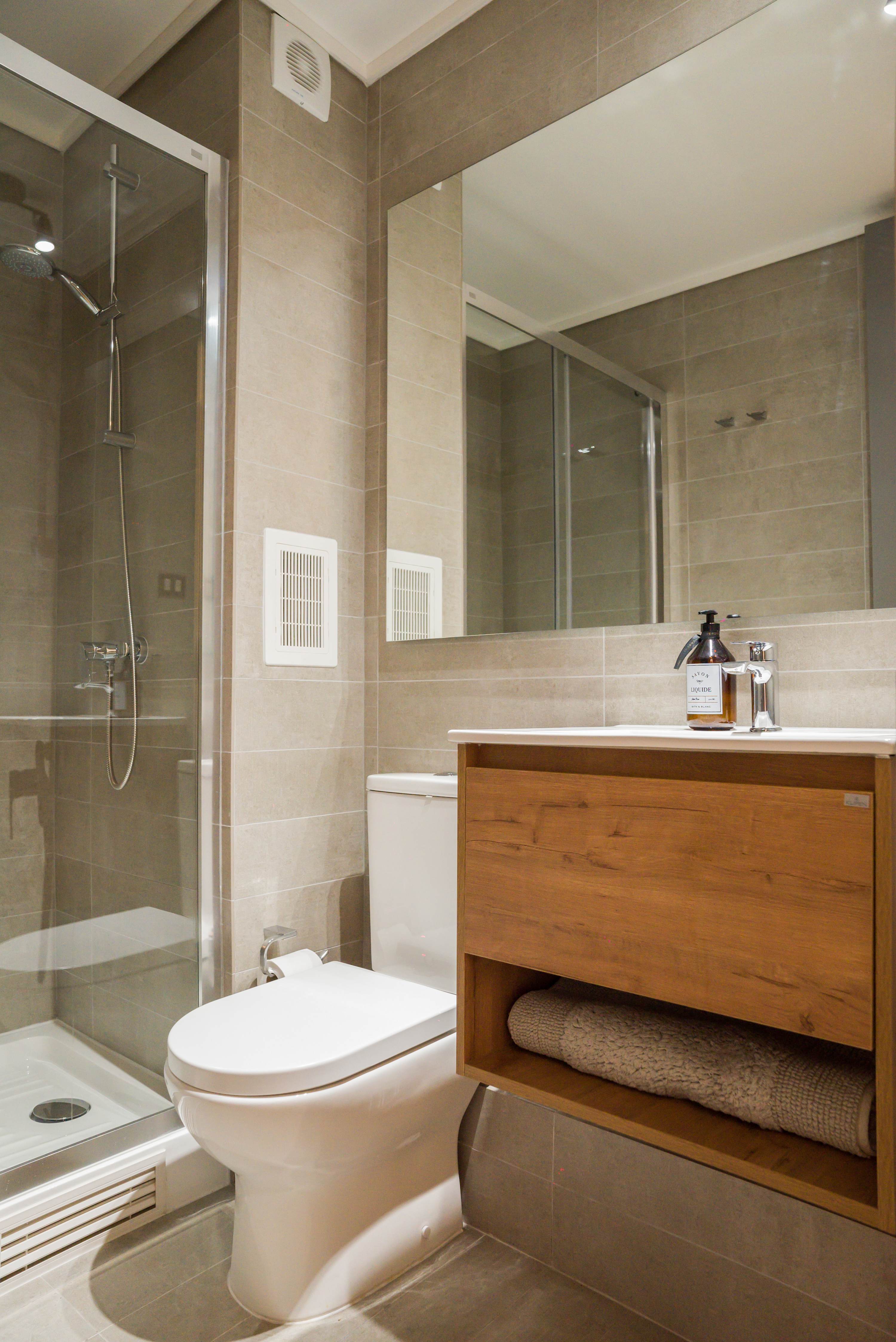 Sleek and modern bathroom with a spacious shower and elegant wooden accents, perfect for a relaxing stay.