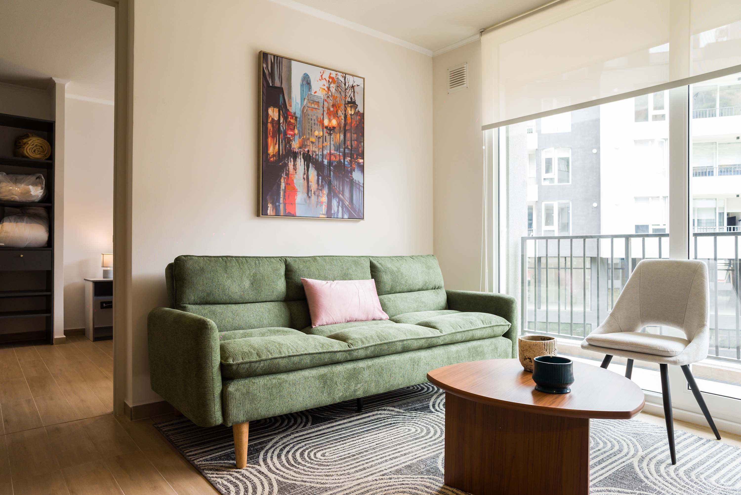 Relax in this stylish living room with a vibrant painting and ample natural light, perfect for unwinding after a day of exploring.
