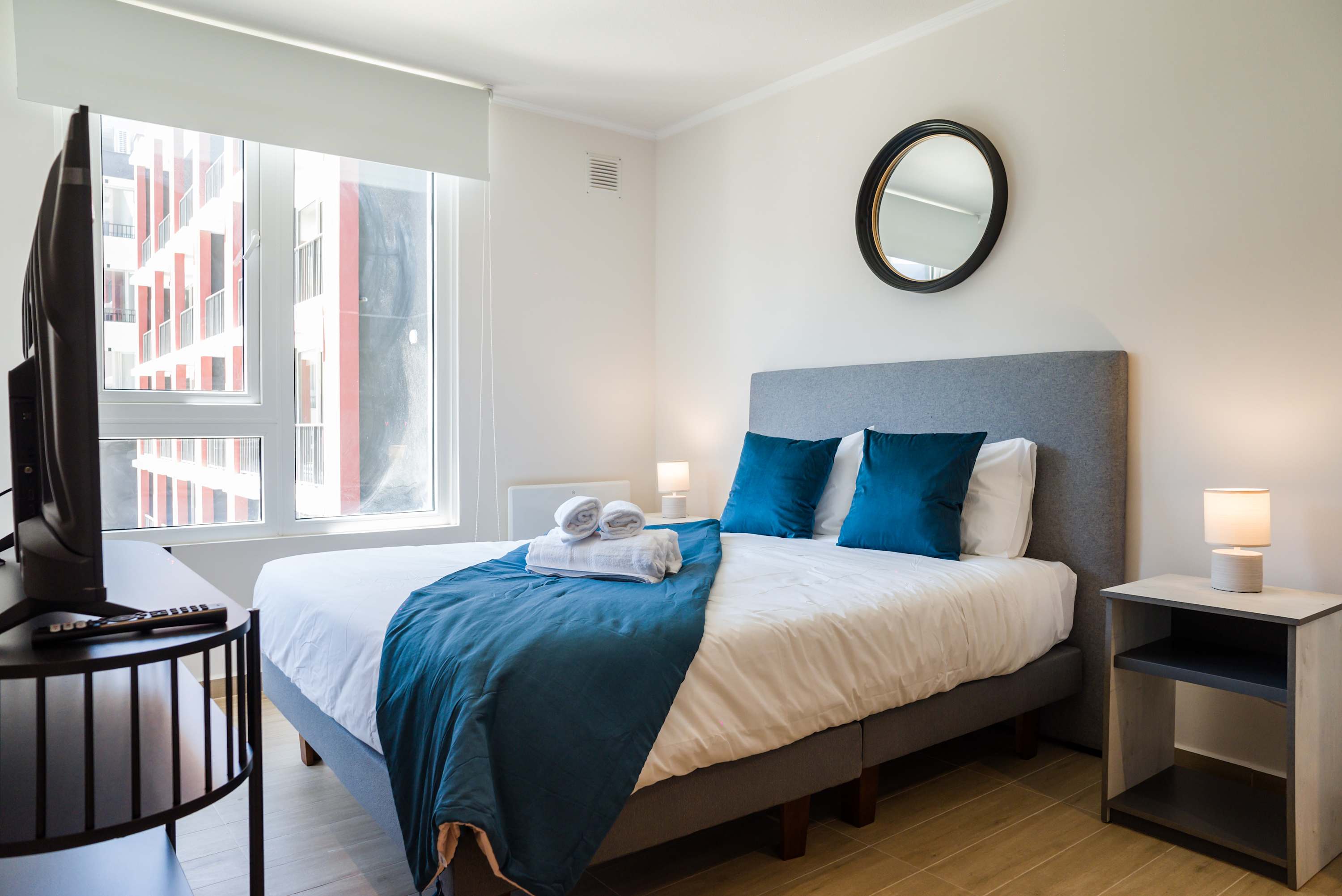 Bright and cozy bedroom with modern decor and ample natural light, perfect for a restful stay.