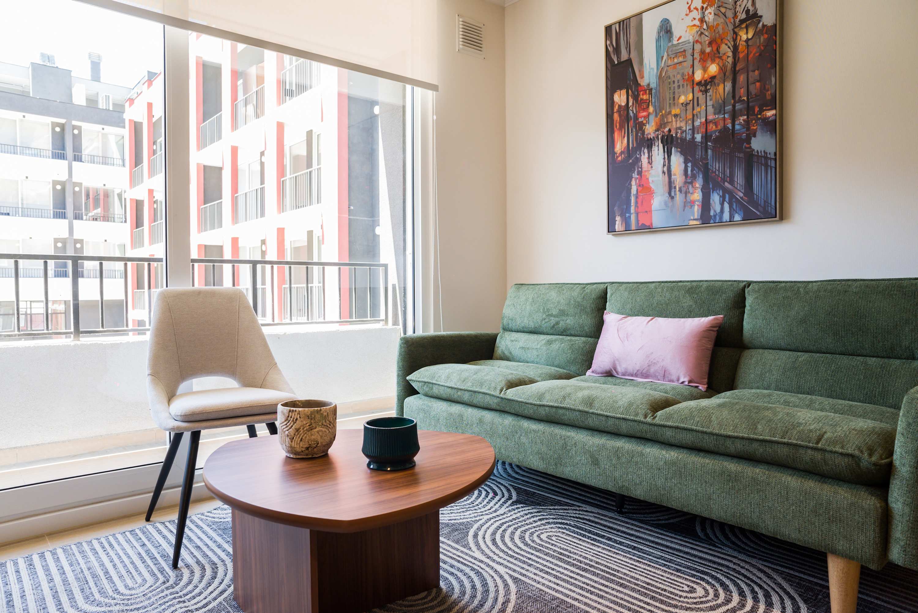 Relax in this stylish living room with a comfy sofa and vibrant cityscape art, perfect for unwinding after a day of exploring.