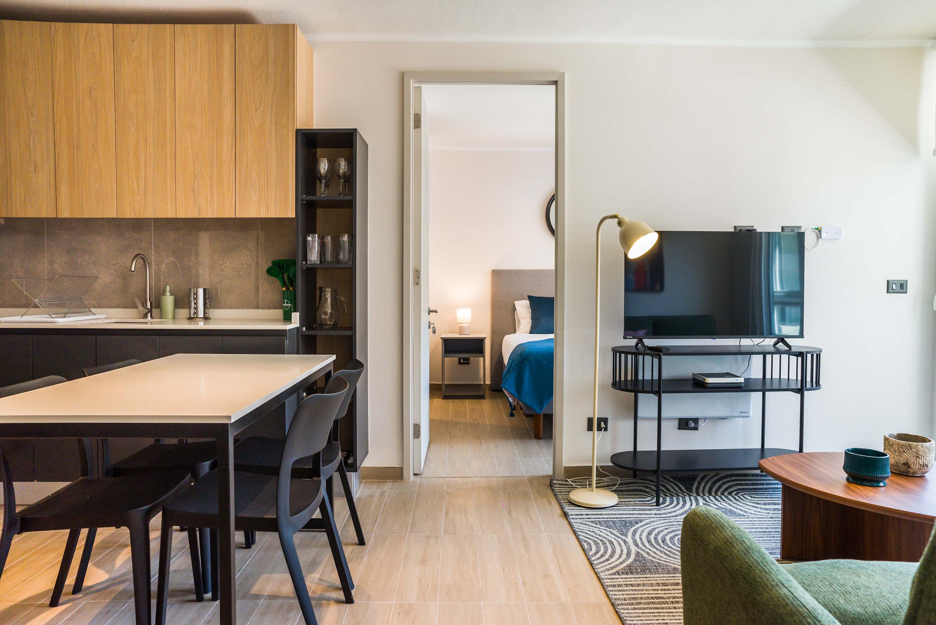 Modern living space with open kitchen and cozy bedroom view, perfect for a relaxing stay.