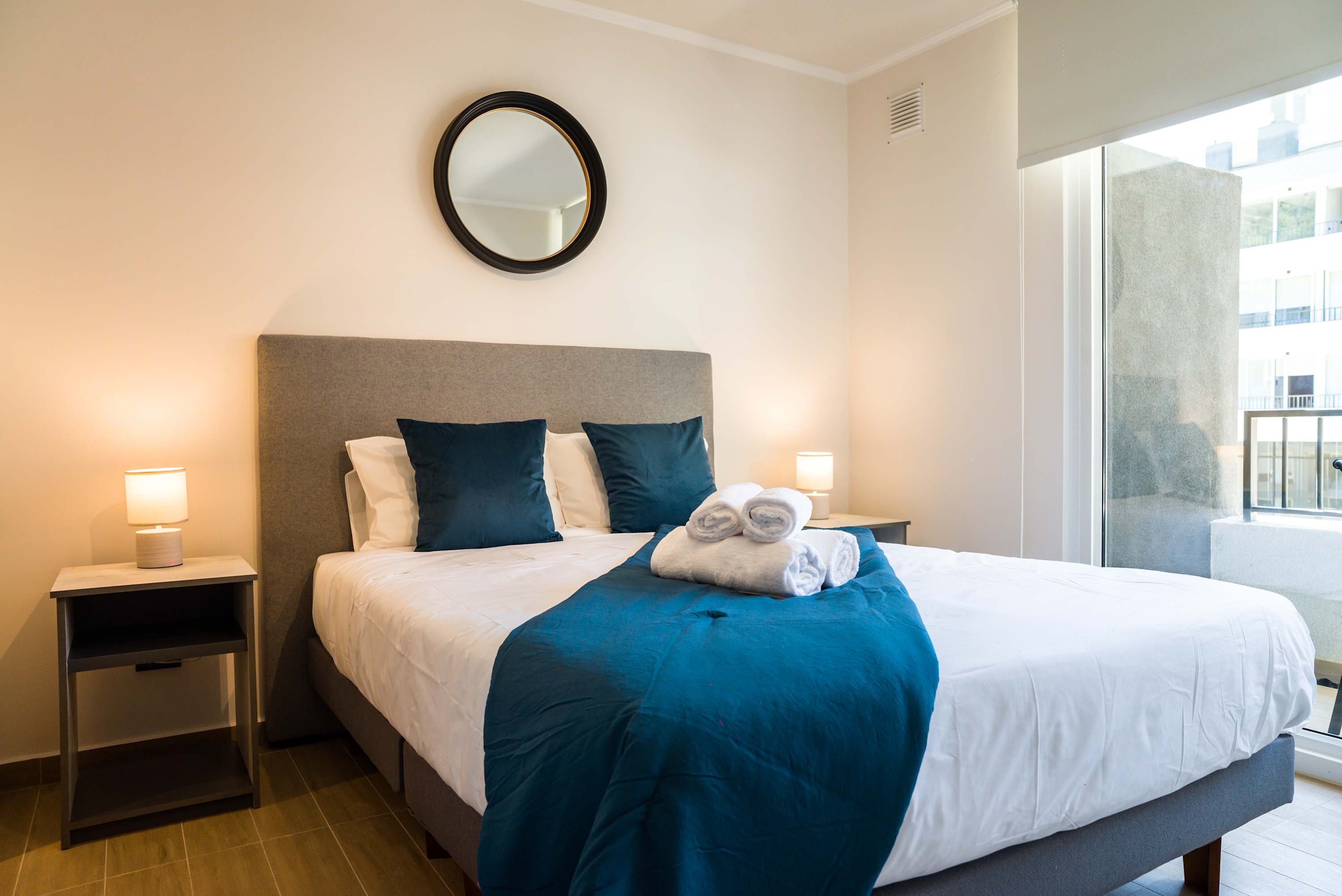 Relax in this cozy bedroom with plush bedding and ample natural light, perfect for unwinding after a day exploring the city.