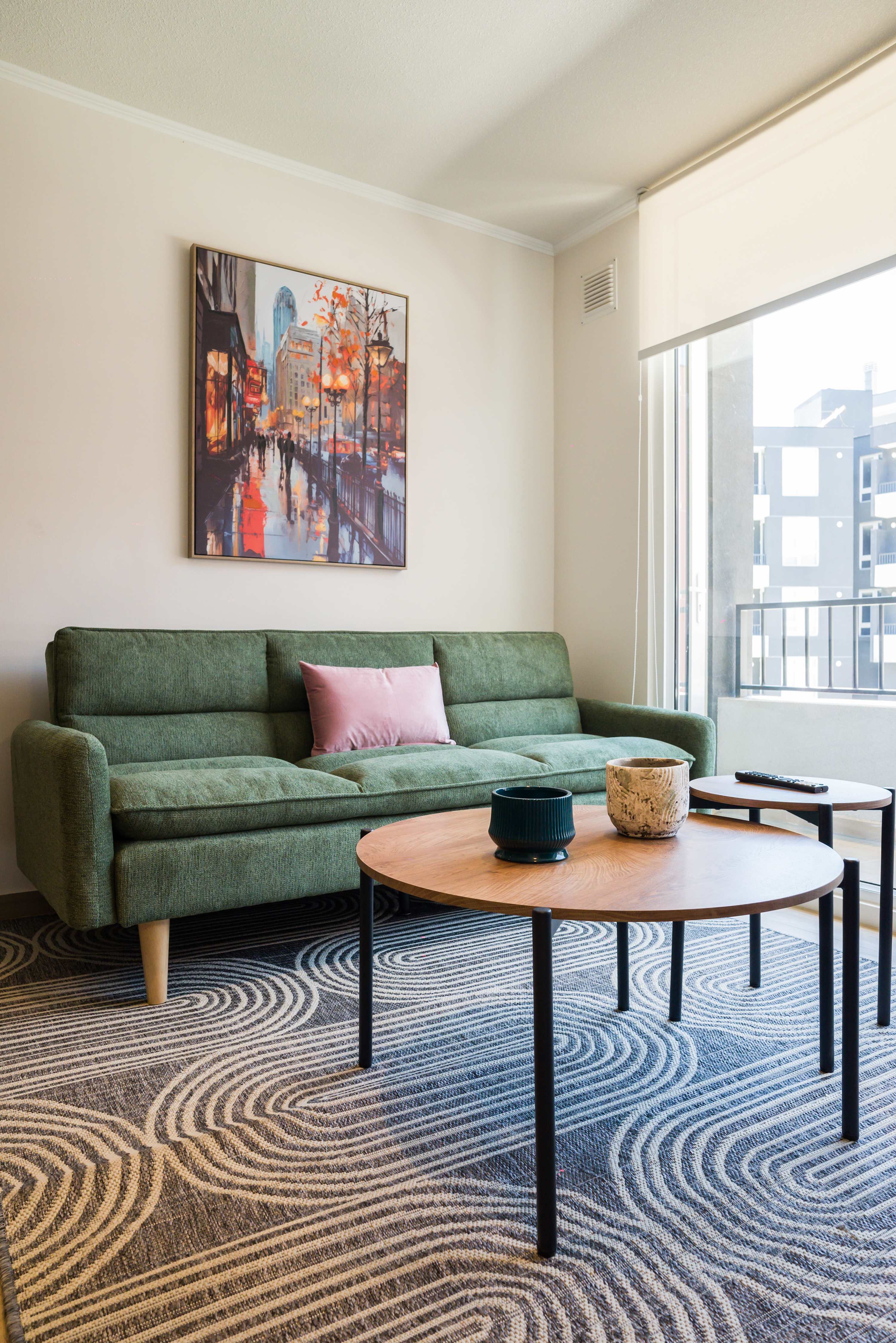 Relax in this stylish living room with a comfy green sofa and vibrant cityscape art, perfect for unwinding after a day of exploring.