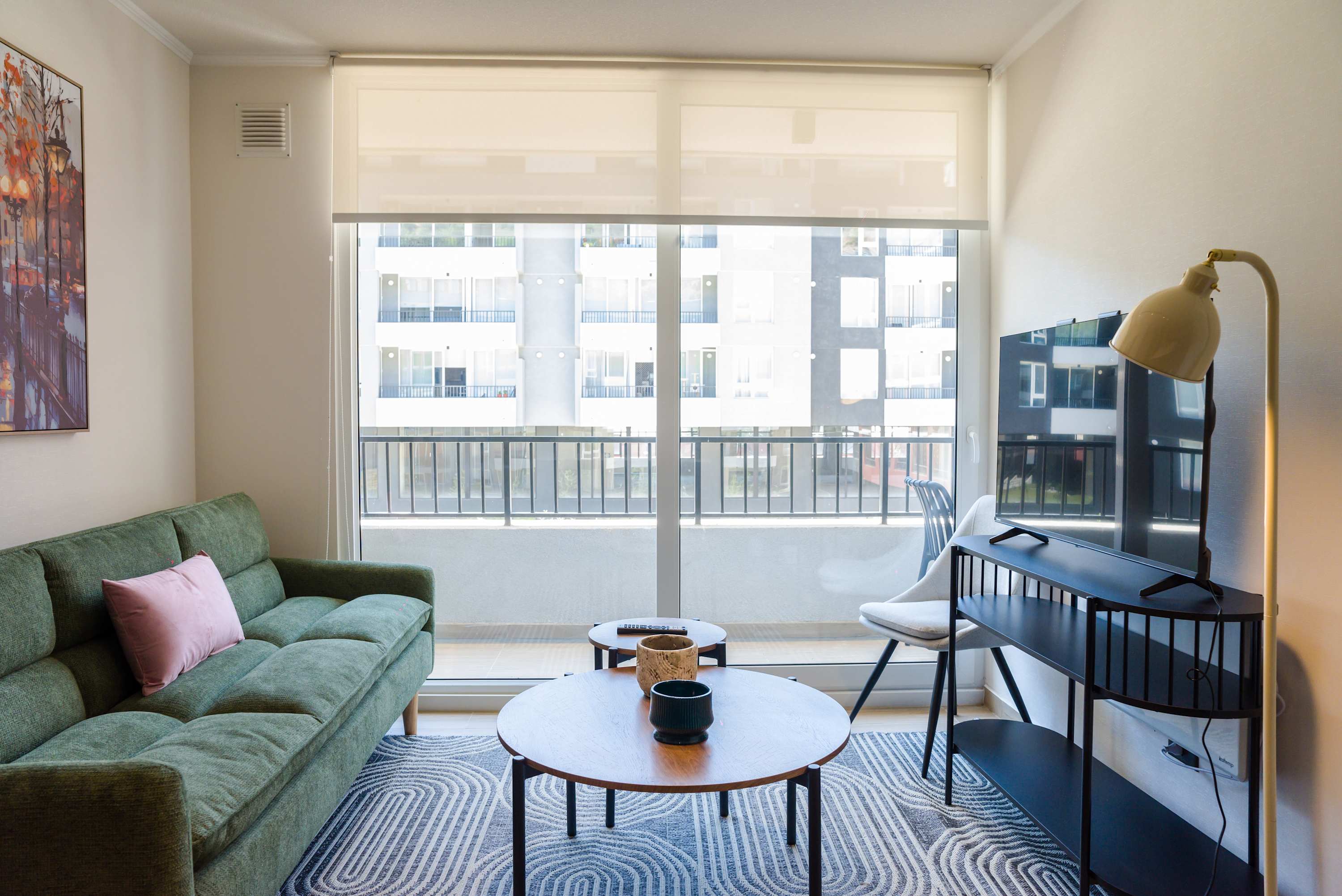 Bright and cozy living room with a comfy sofa and large windows offering city views, perfect for relaxation.