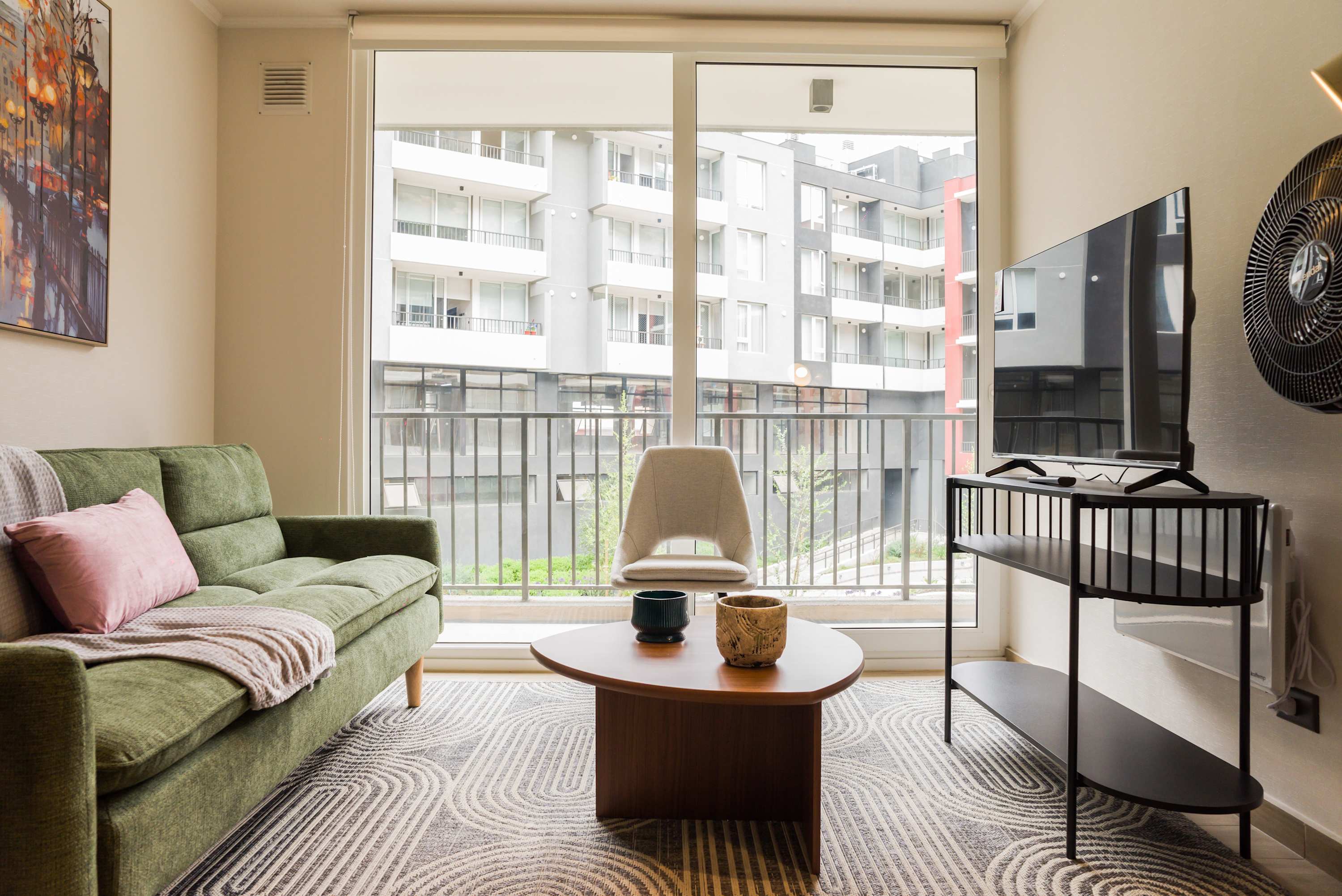 Bright and cozy living space with a comfortable sofa and large windows offering a city view.