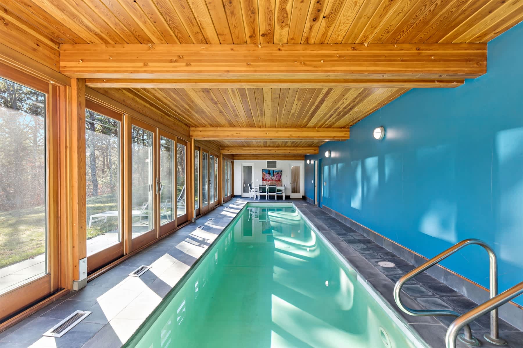 Heated indoor lap pool with a wall of windows and seating areas, perfect for morning laps, relaxing swims, or unwinding after a day on the Outer Cape.