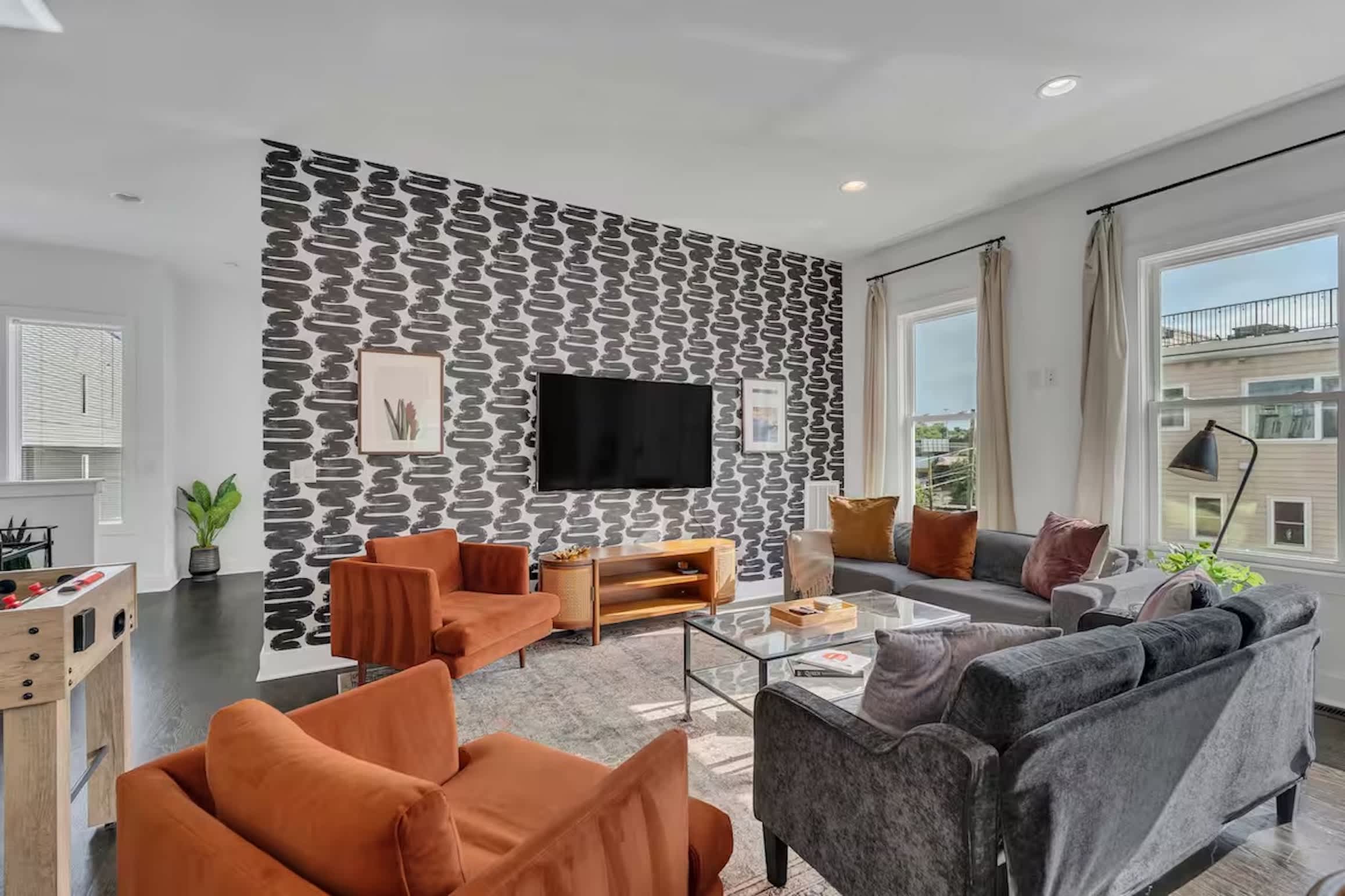 Open-concept living with foosball table, plush seating, and a bright, modern kitchen. | Unit A