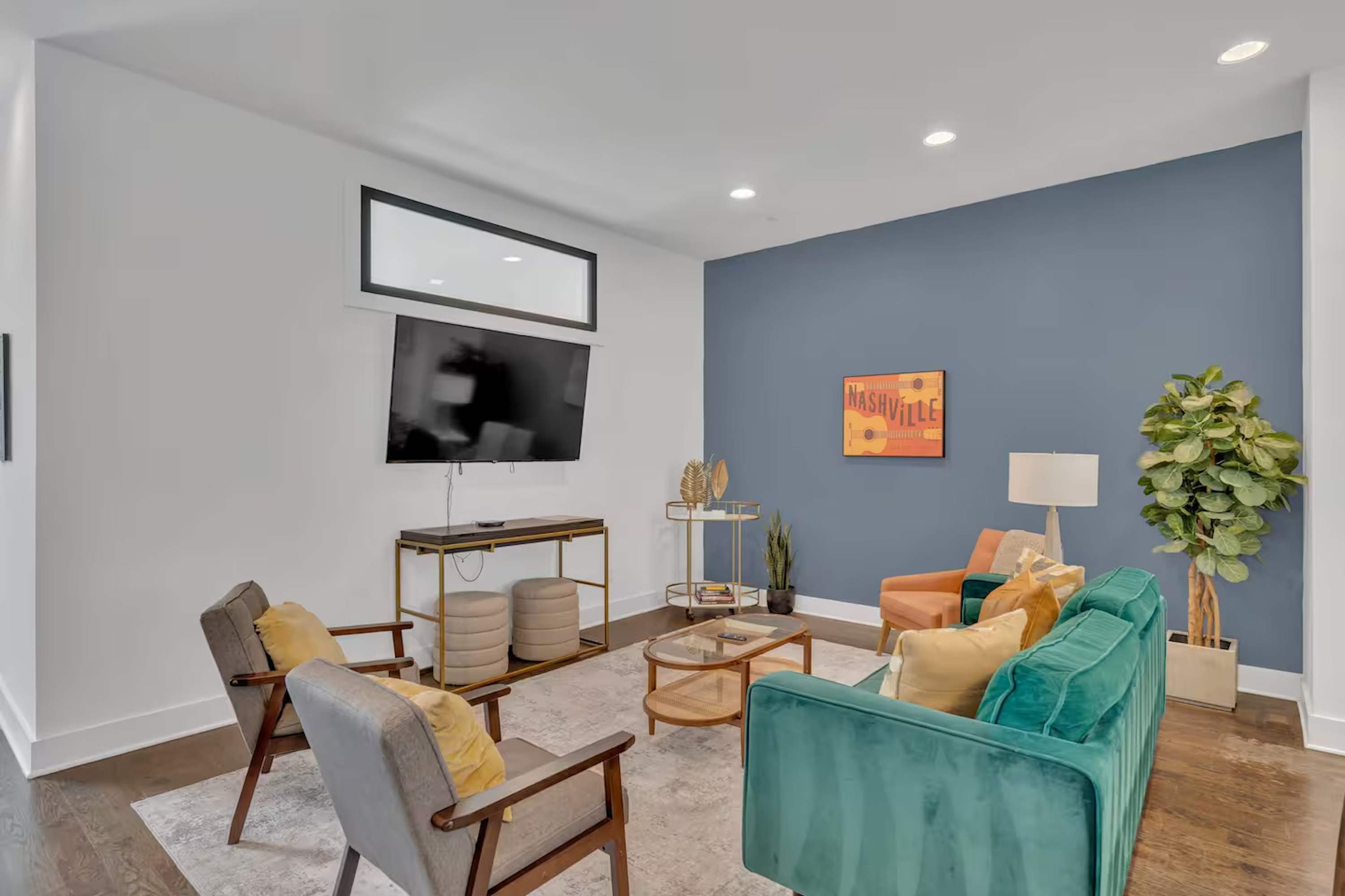 Open-concept living room with plush seating, large windows, and a chef's kitchen. | Unit B