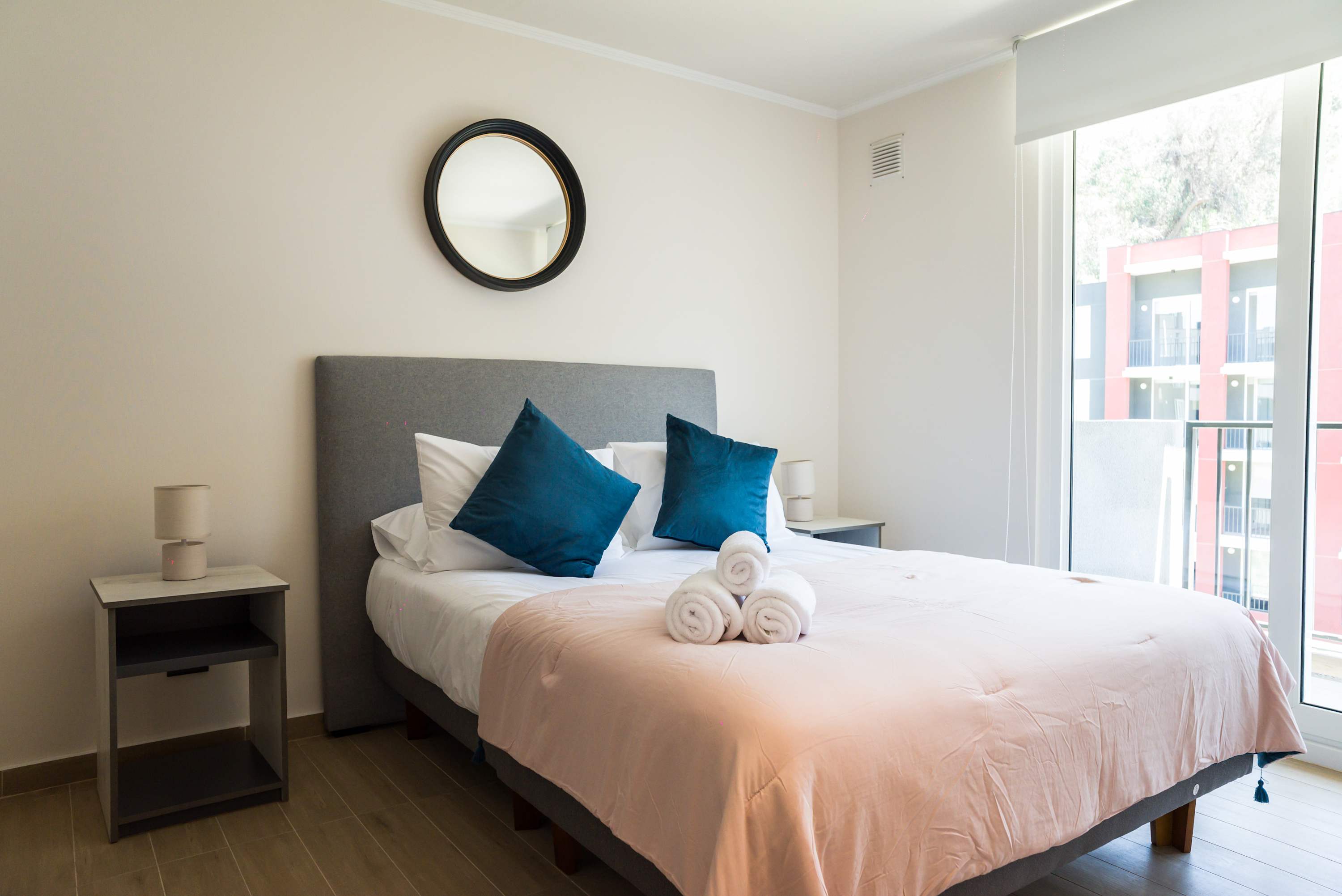 Relax in this bright and cozy bedroom with plush bedding and natural light from the large window.