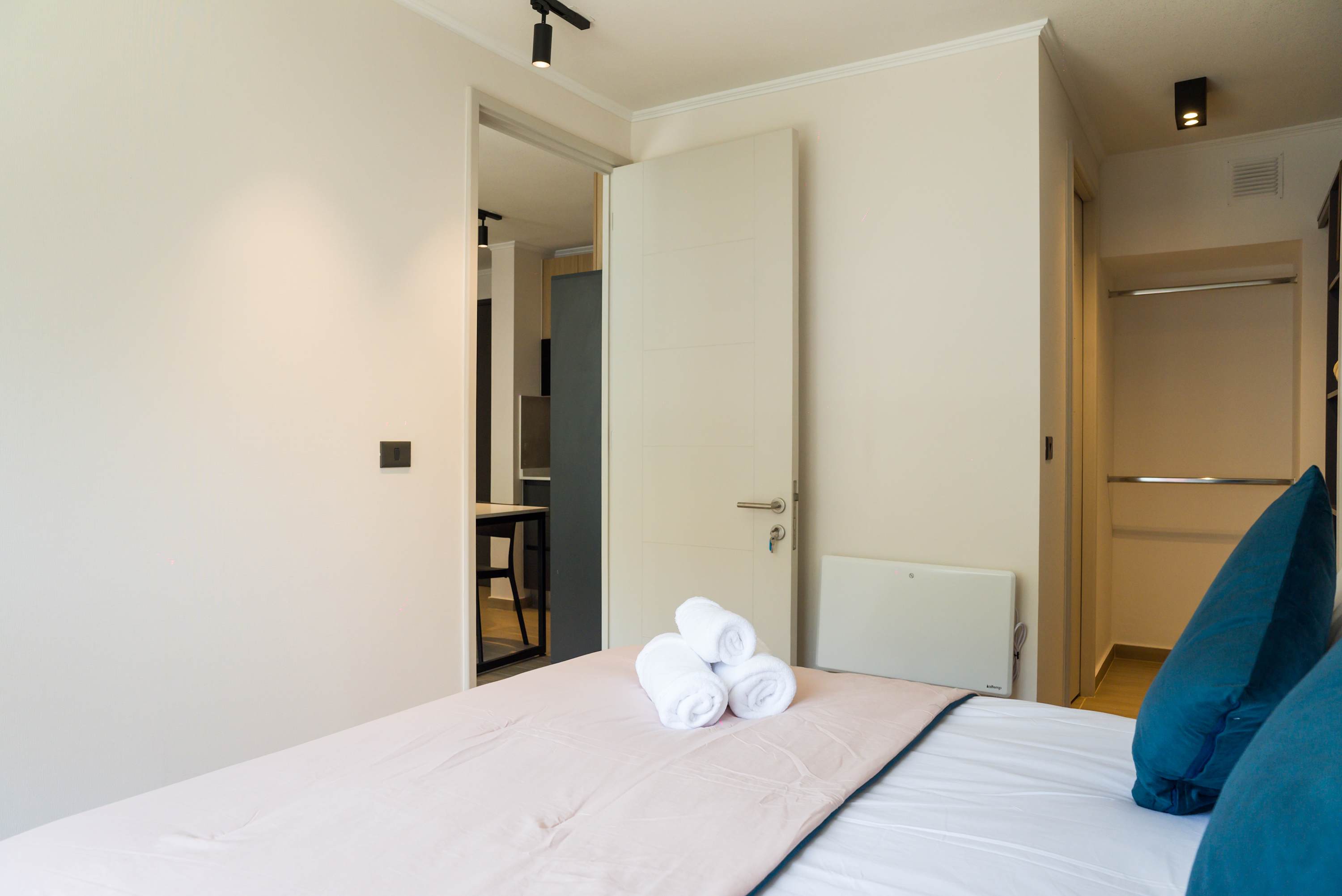 Relax in this cozy bedroom with plush bedding and modern decor, perfect for a restful stay.