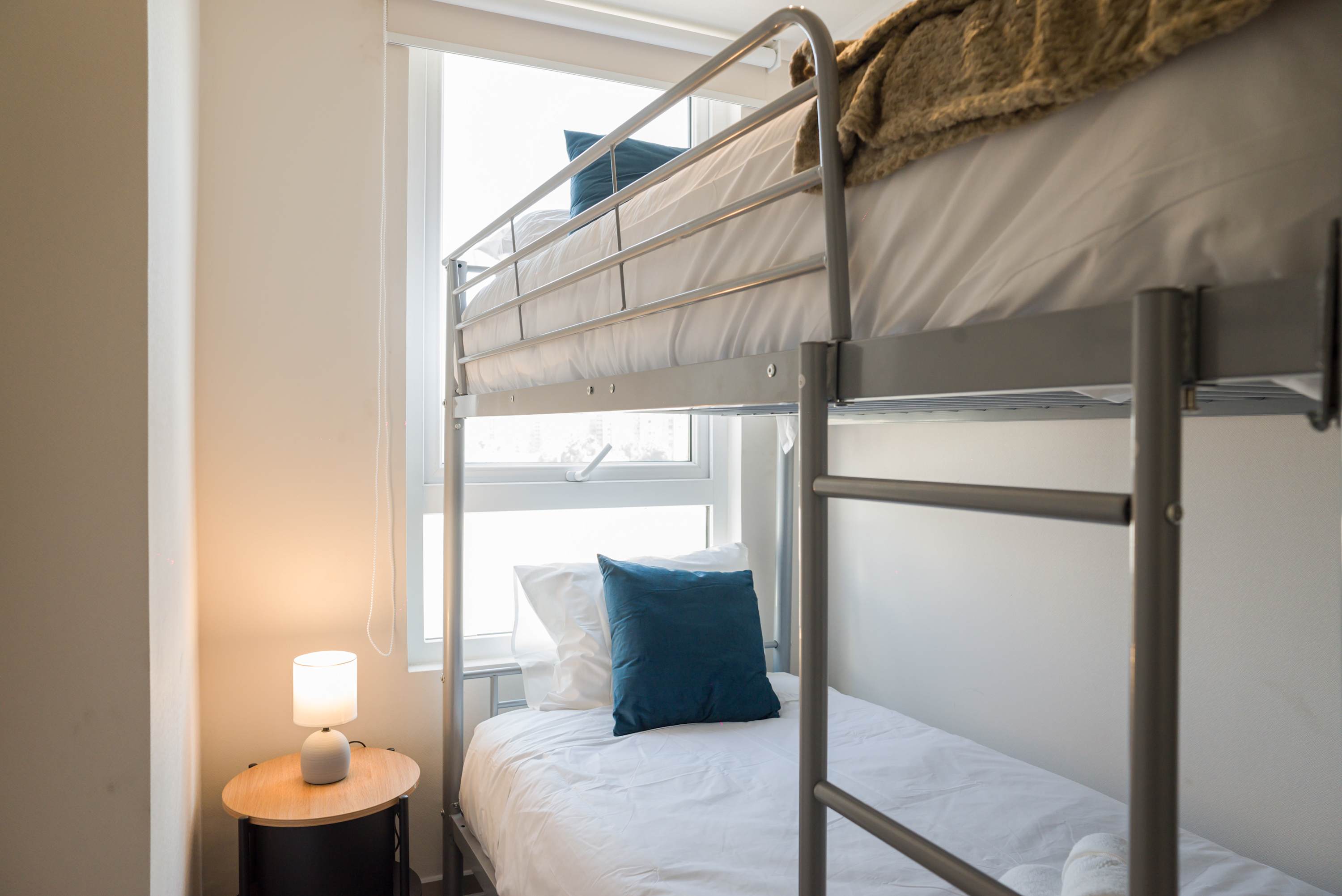 Cozy bunk bed setup with soft lighting and natural daylight, perfect for a restful stay.