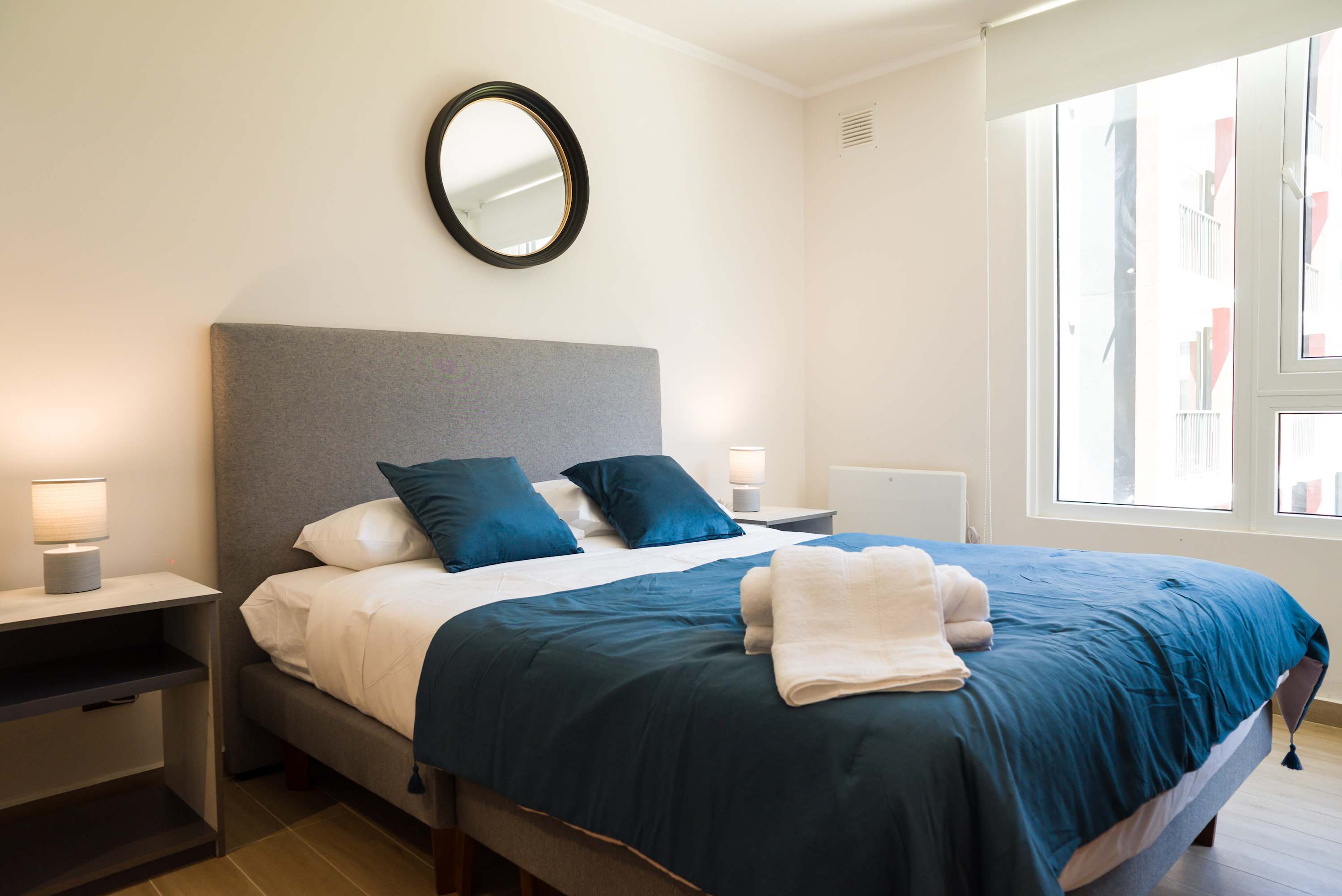 Relax in this cozy bedroom with plush bedding and ample natural light, perfect for a restful stay.