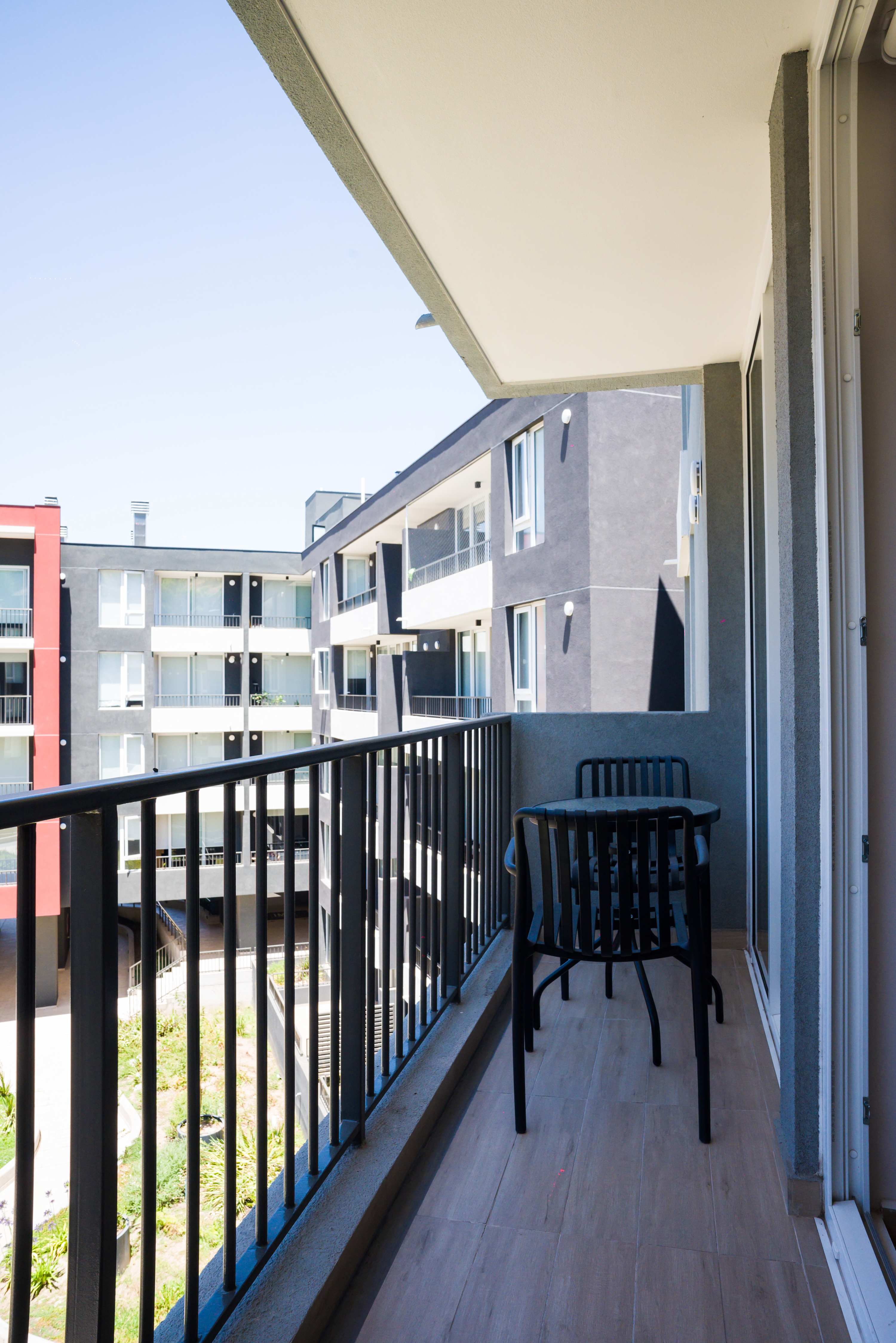 Enjoy a cozy morning coffee on your private balcony with views of modern architecture.