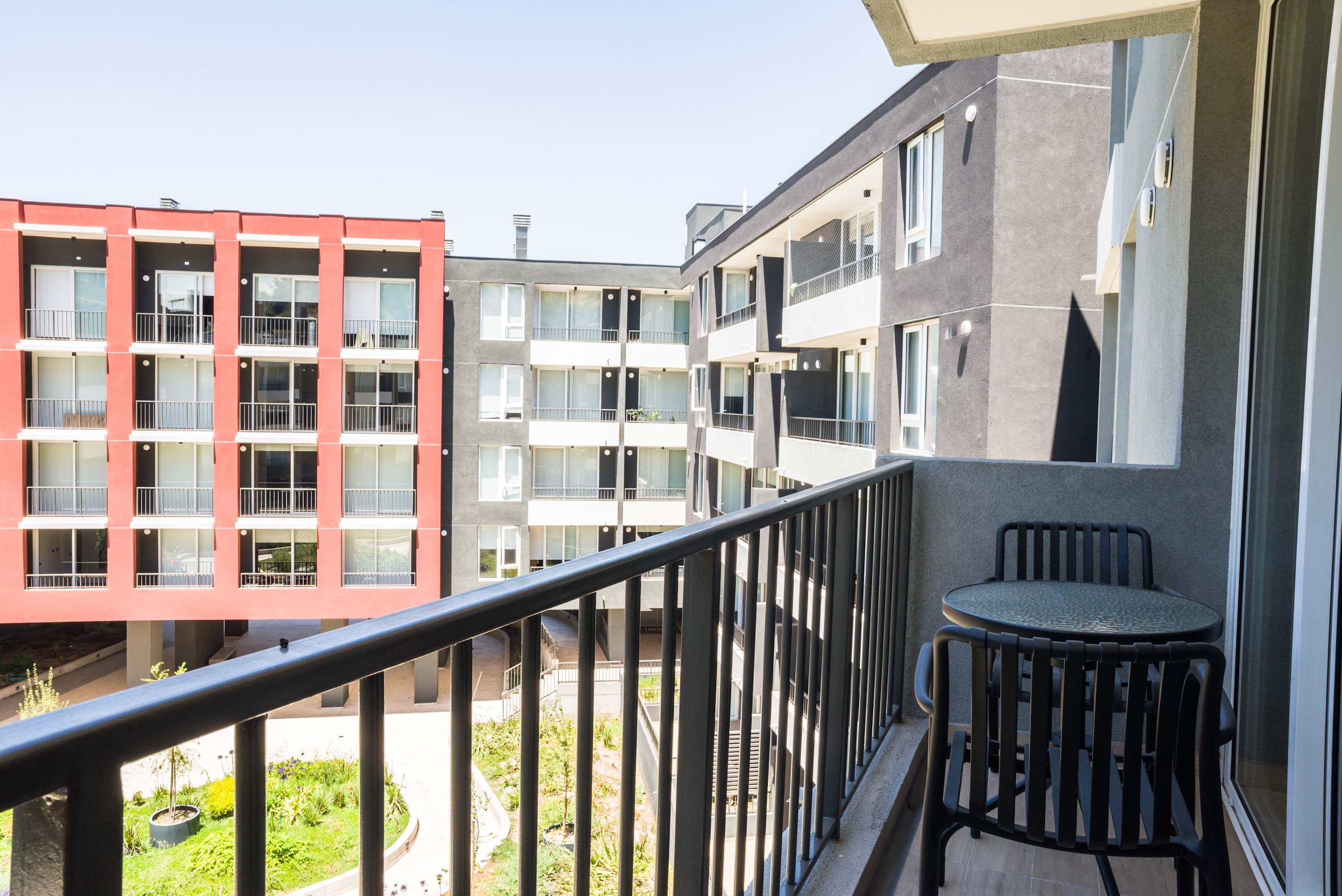 Enjoy a relaxing moment on your private balcony with views of the vibrant courtyard and modern architecture.