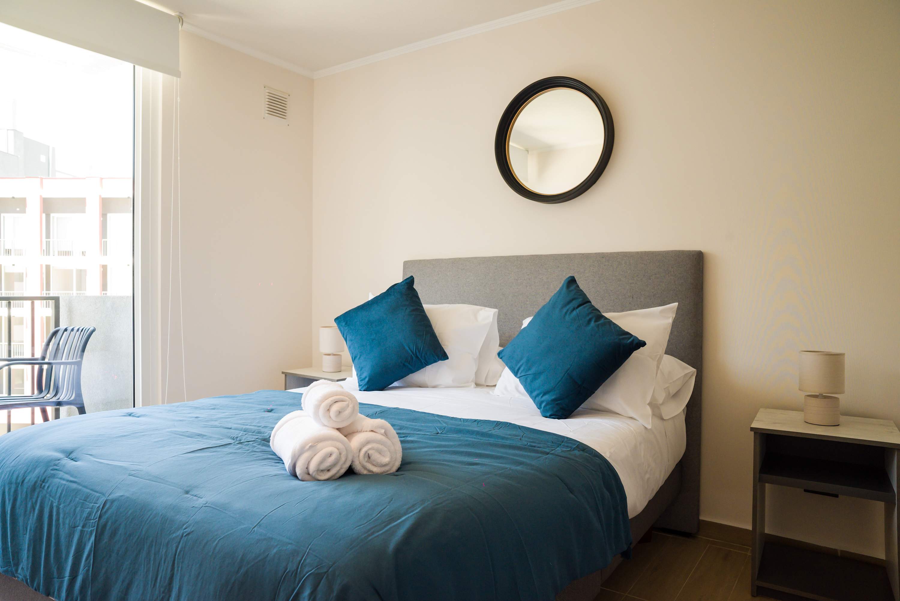 Cozy bedroom with plush bedding and natural light, perfect for a restful stay.