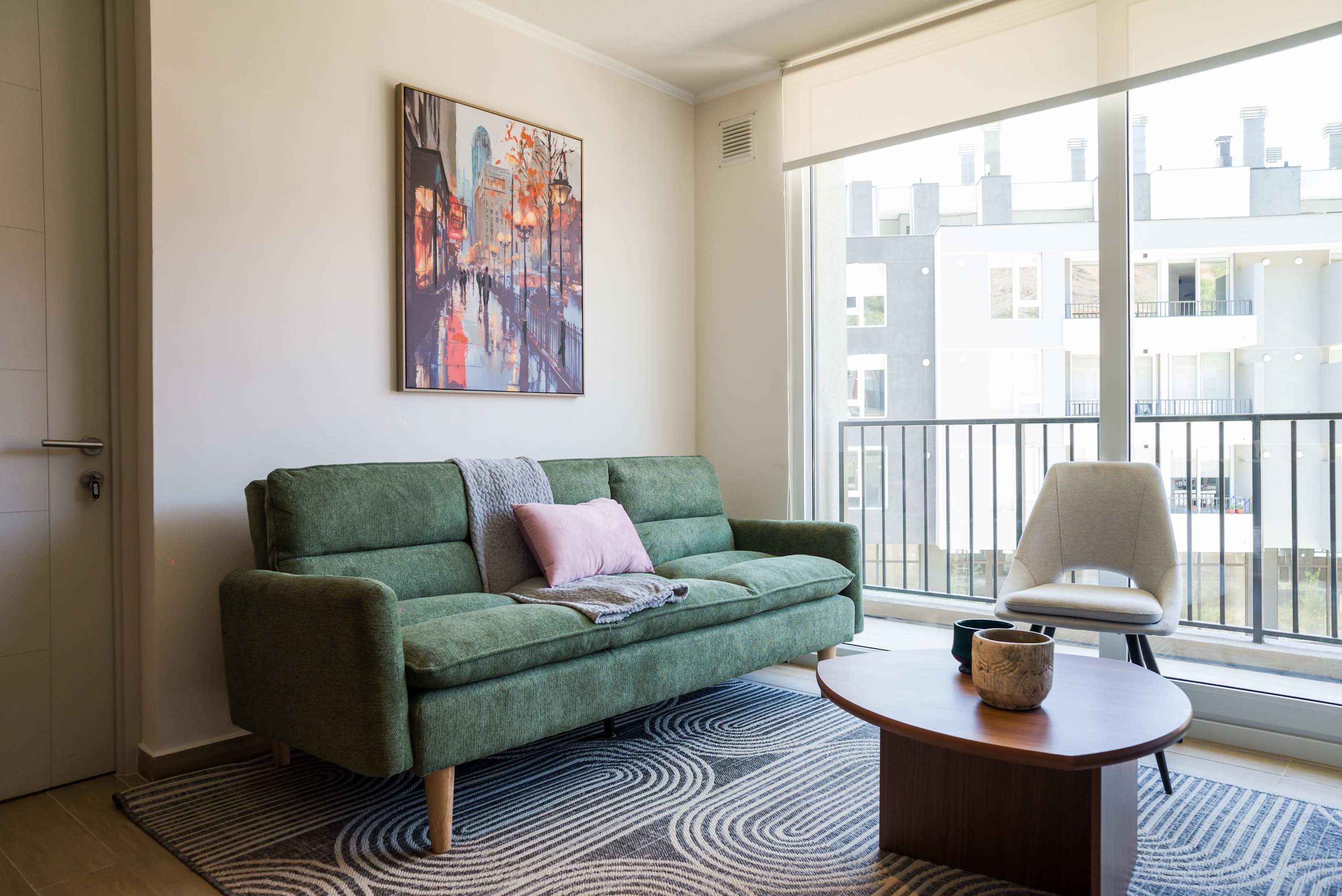 Relax in this stylish living room with a comfy green sofa and vibrant artwork, perfect for unwinding after exploring the city.