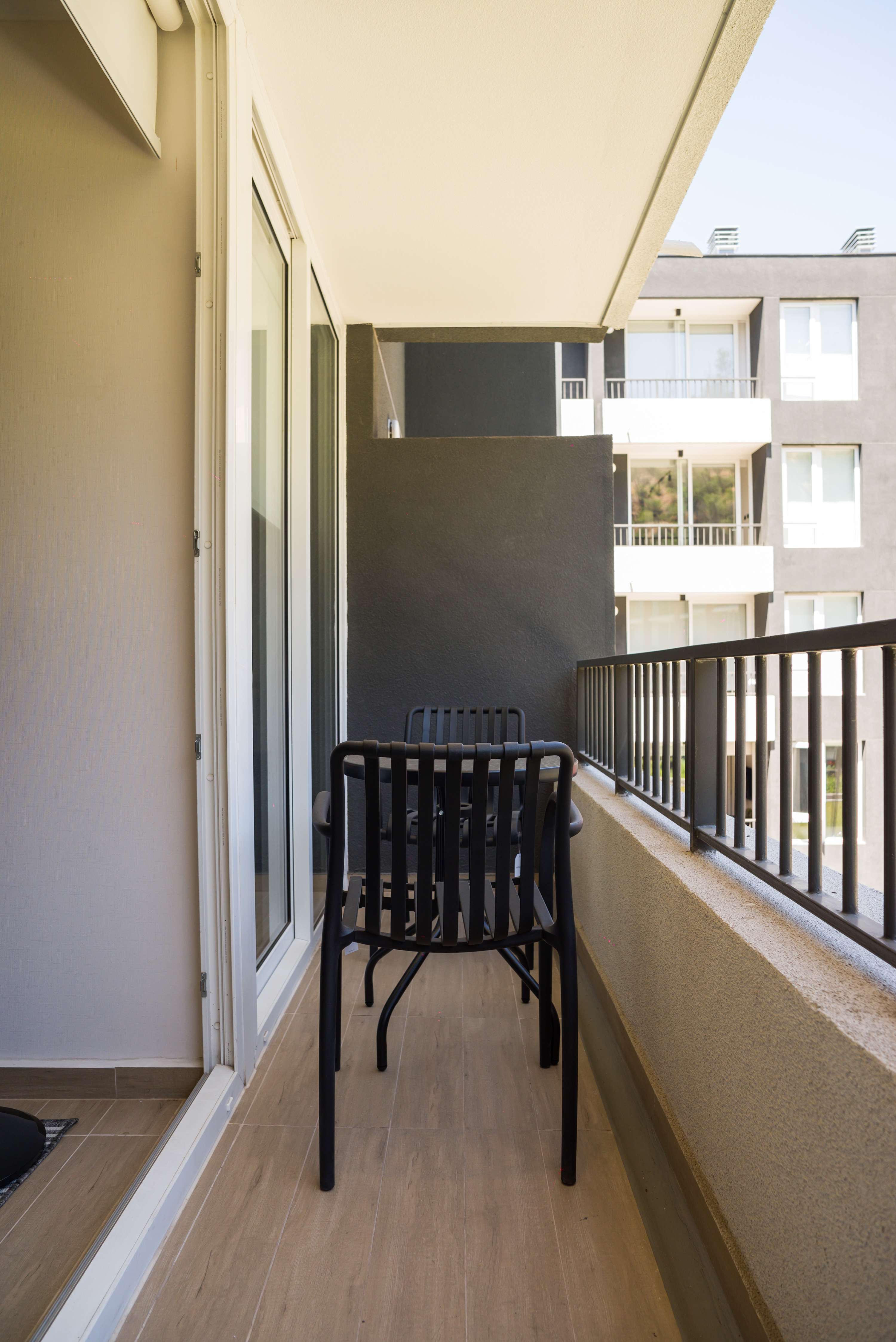 Enjoy a relaxing moment on your private balcony with modern seating and a view of the cityscape.