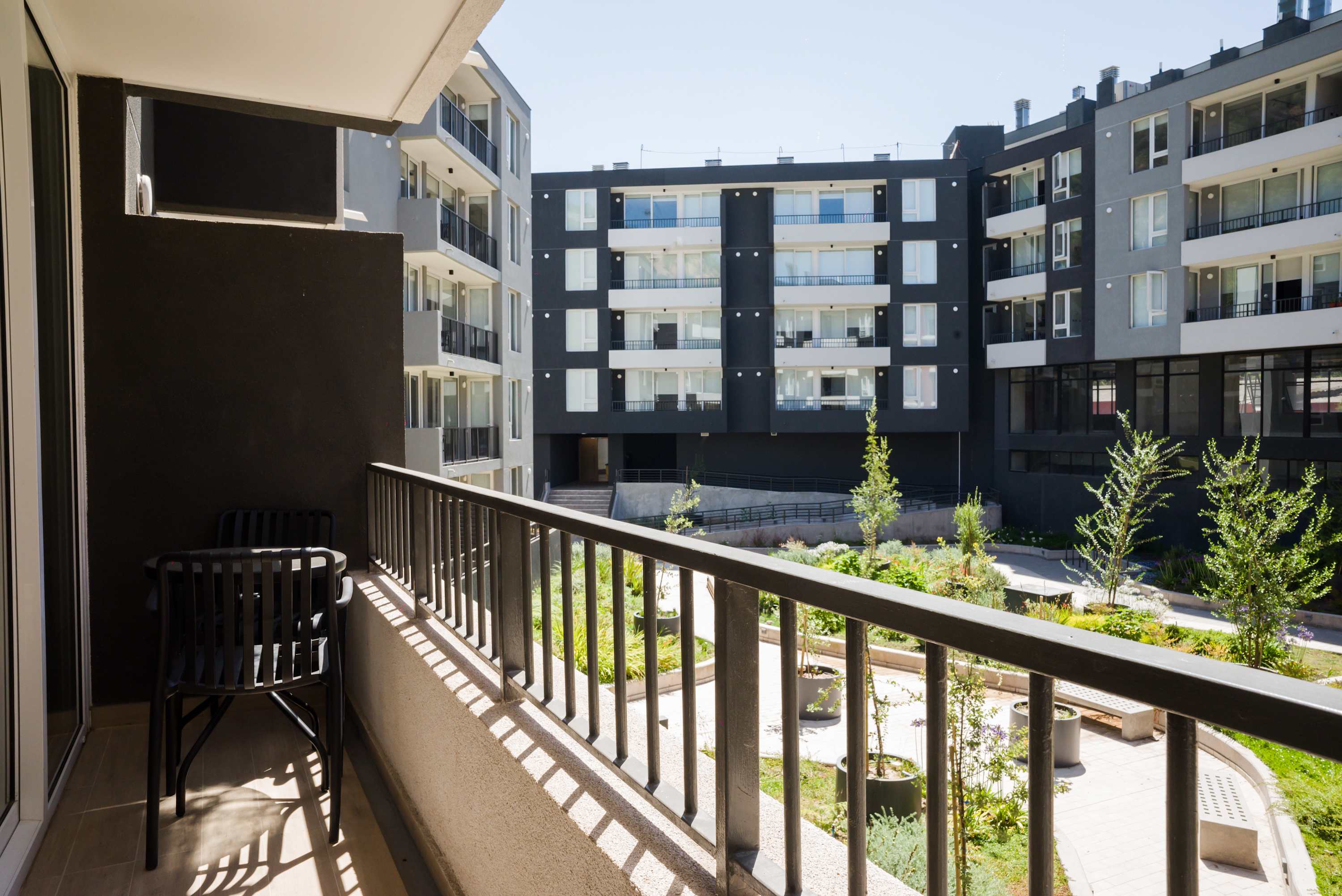 Enjoy your morning coffee on this private balcony with views of the lush courtyard and modern architecture.