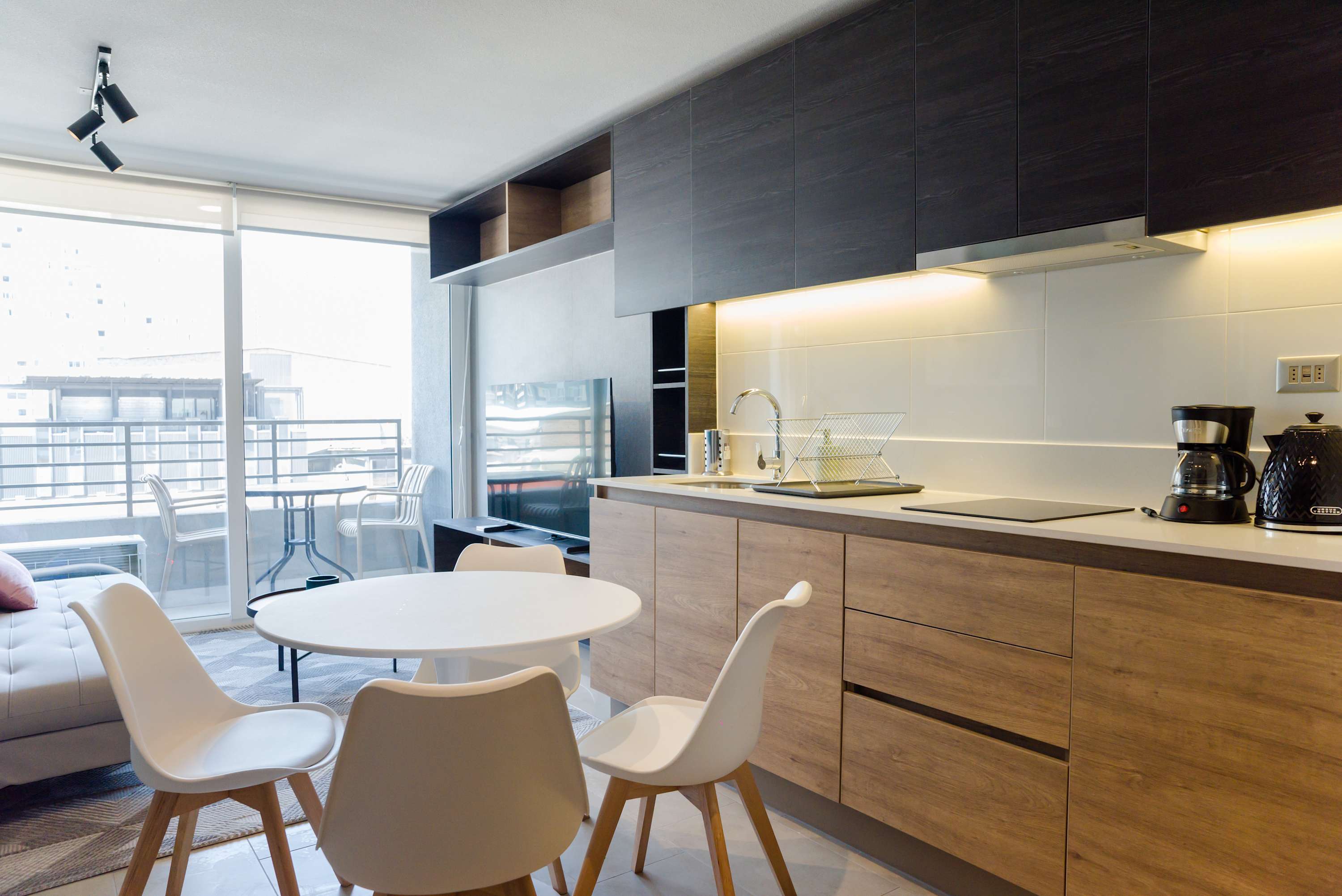 Bright and modern kitchen with dining area and balcony view, perfect for enjoying meals and relaxing.