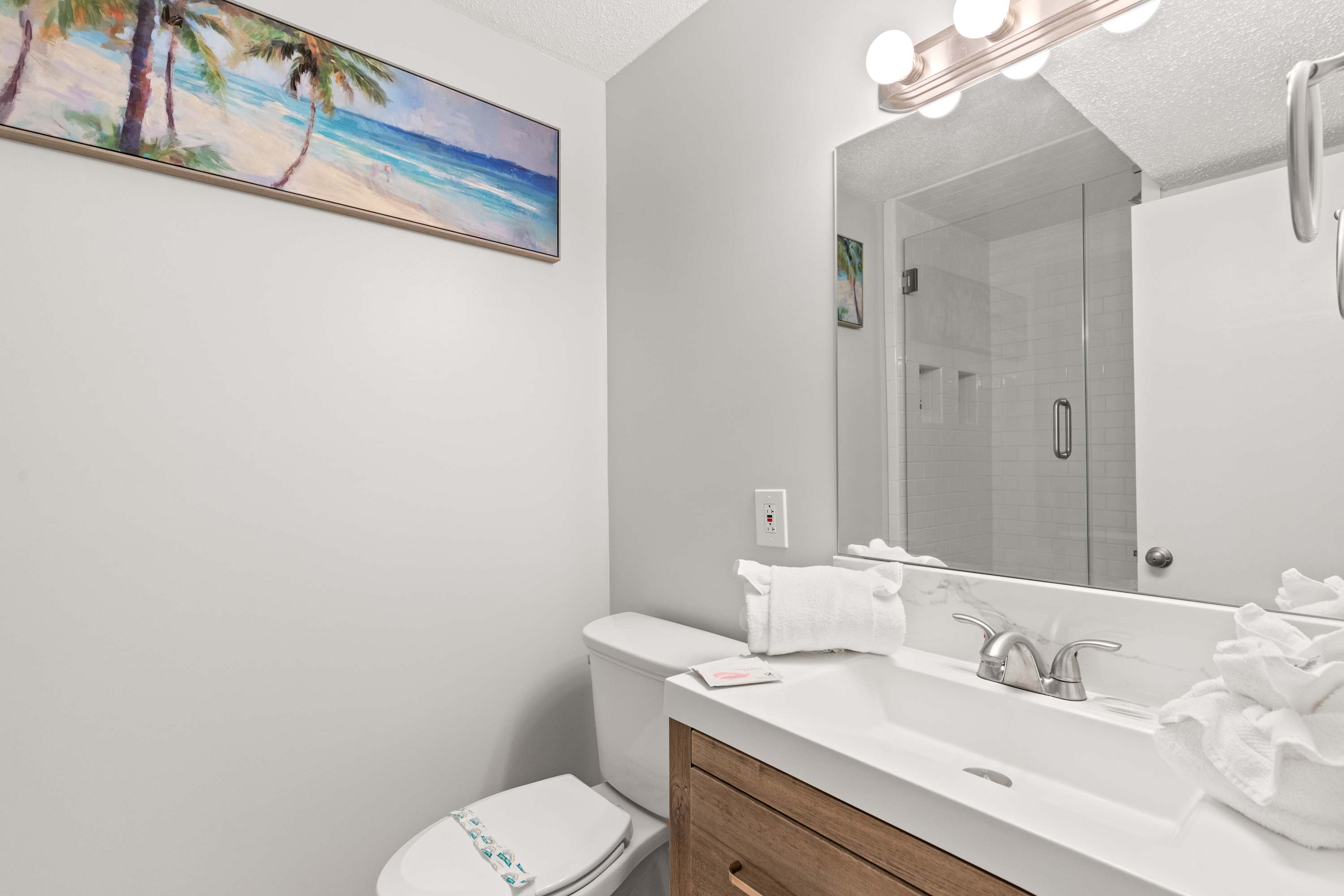 The Summit 1419 – Bathroom featuring a sink, mirror, shower, and artwork of a beach scene.