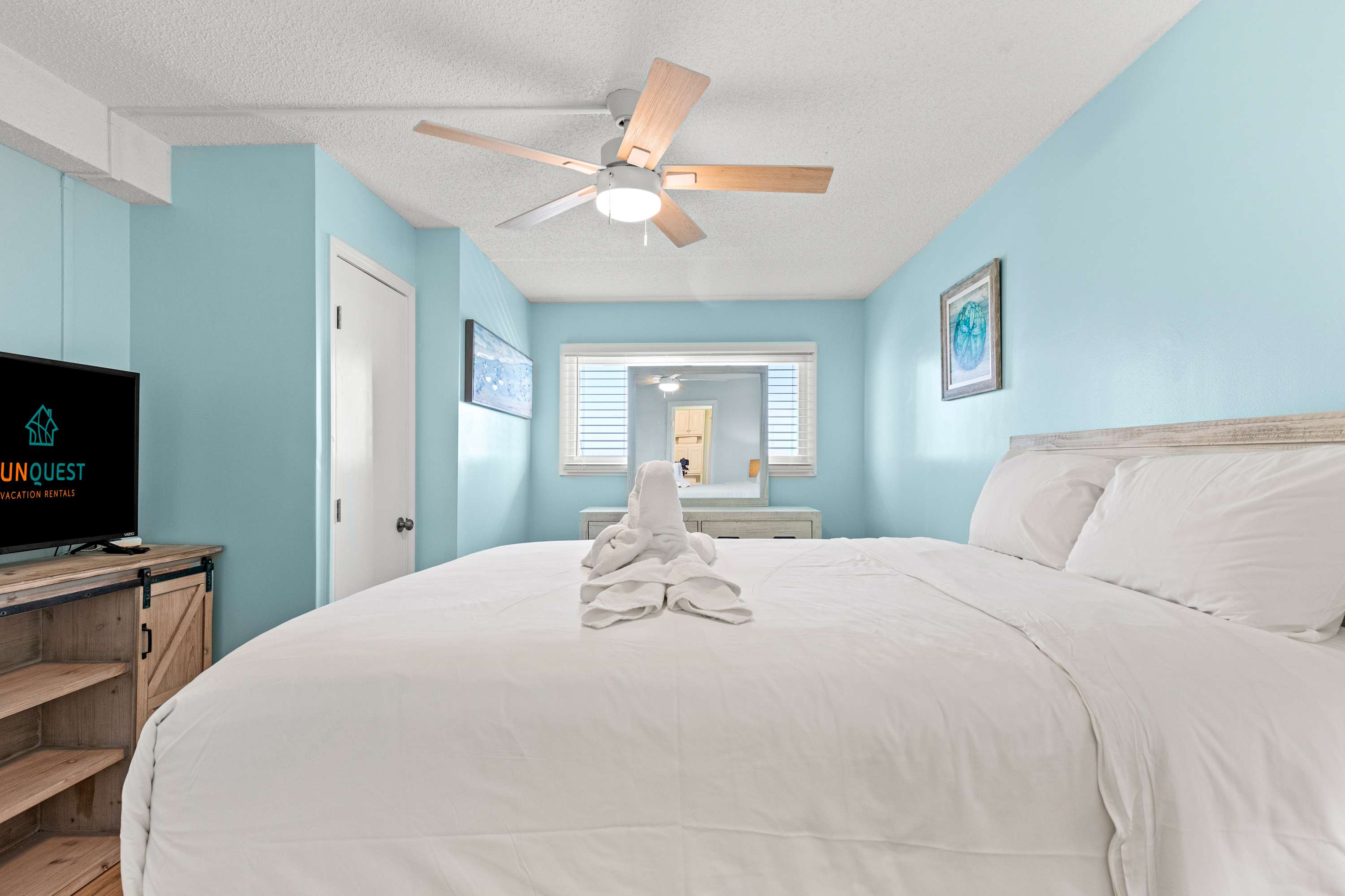 The Summit 1419 – Bright bedroom with a queen bed, blue walls, a ceiling fan, and a TV.