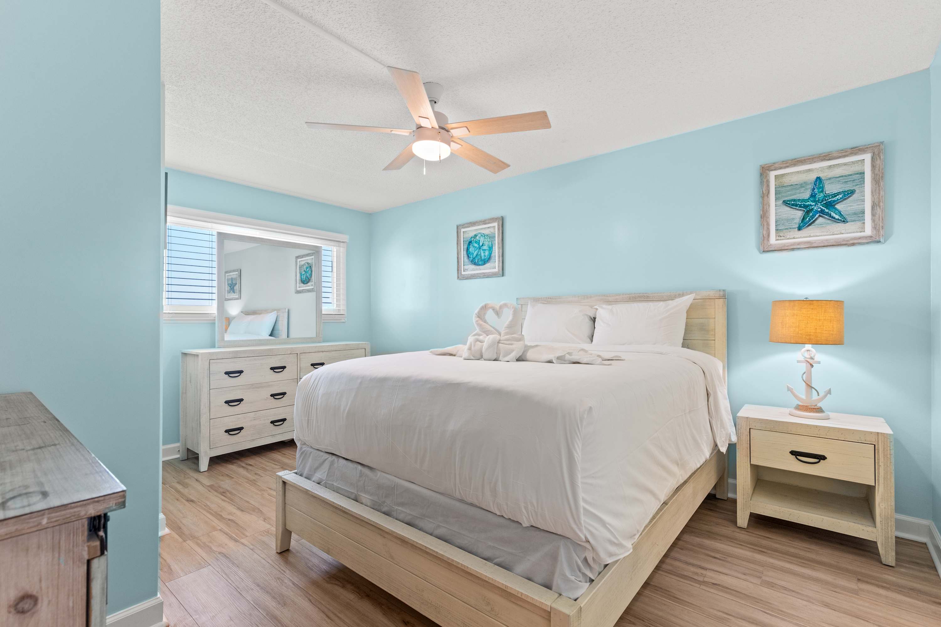The Summit 1419 – Bright bedroom with a queen bed, dresser, and beach-themed decor.