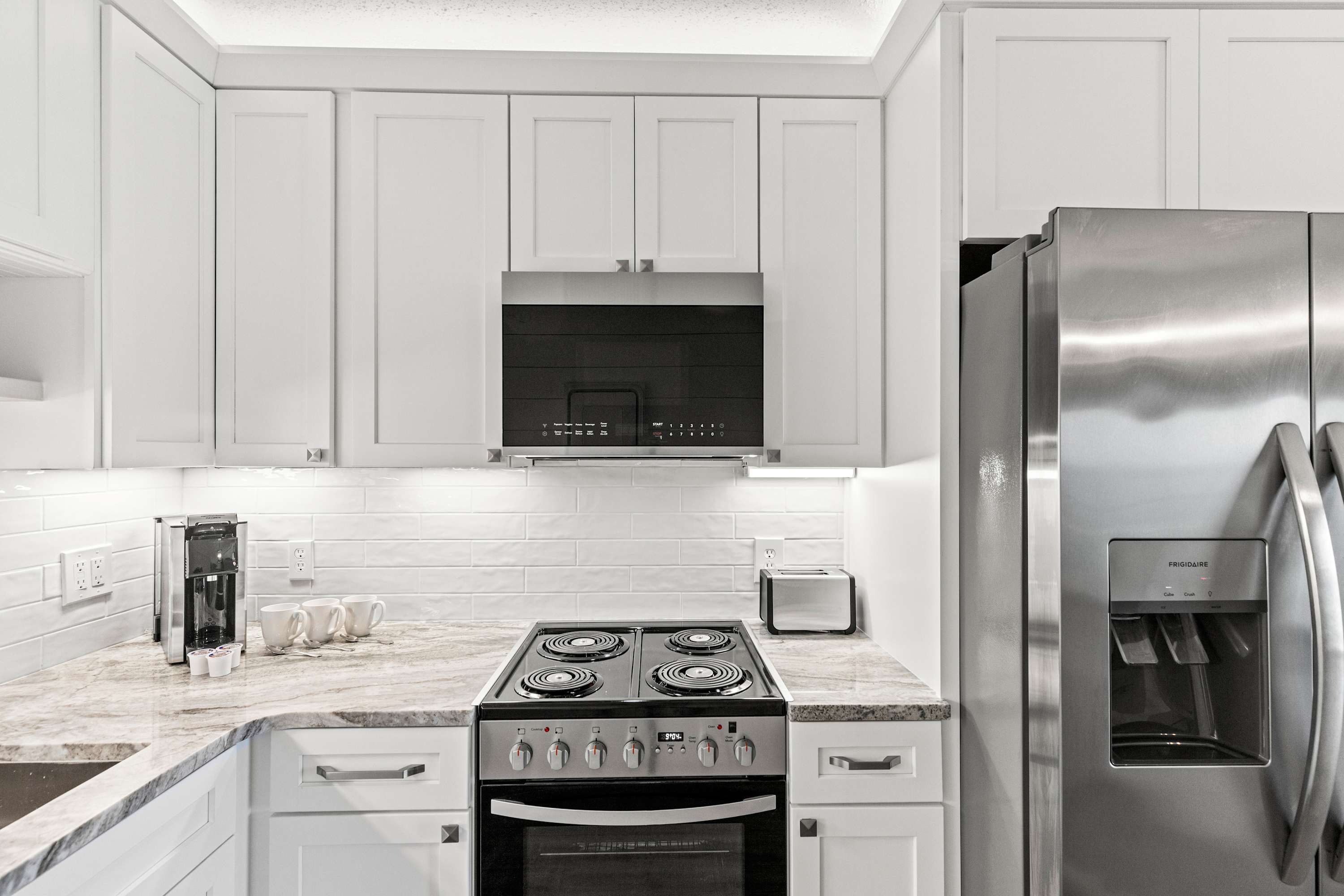 The Summit 1419 – Modern kitchen with white cabinets, granite countertops, stainless steel appliances, and coffee maker.