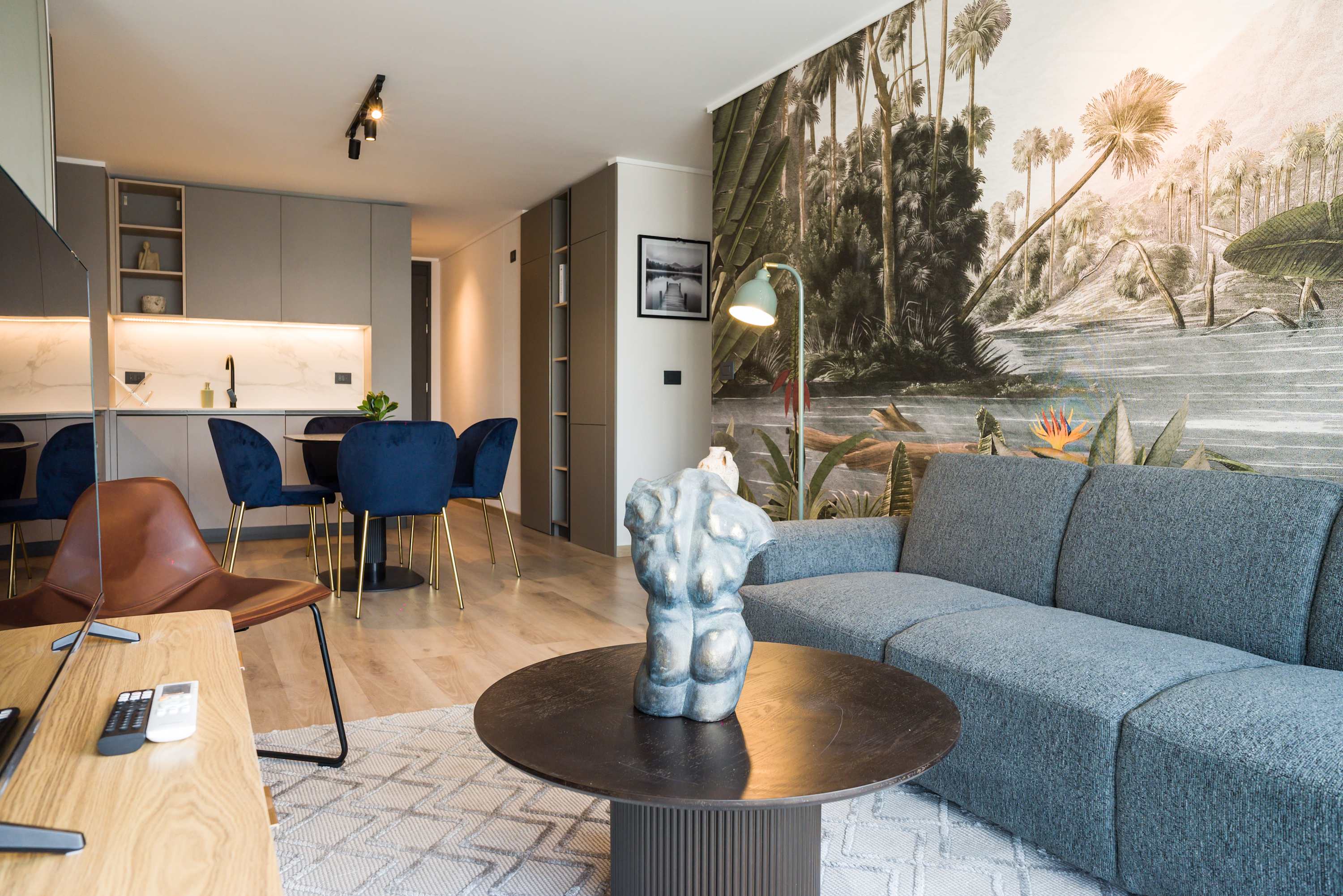 Stylish living area with tropical mural and modern decor, perfect for relaxation and dining.