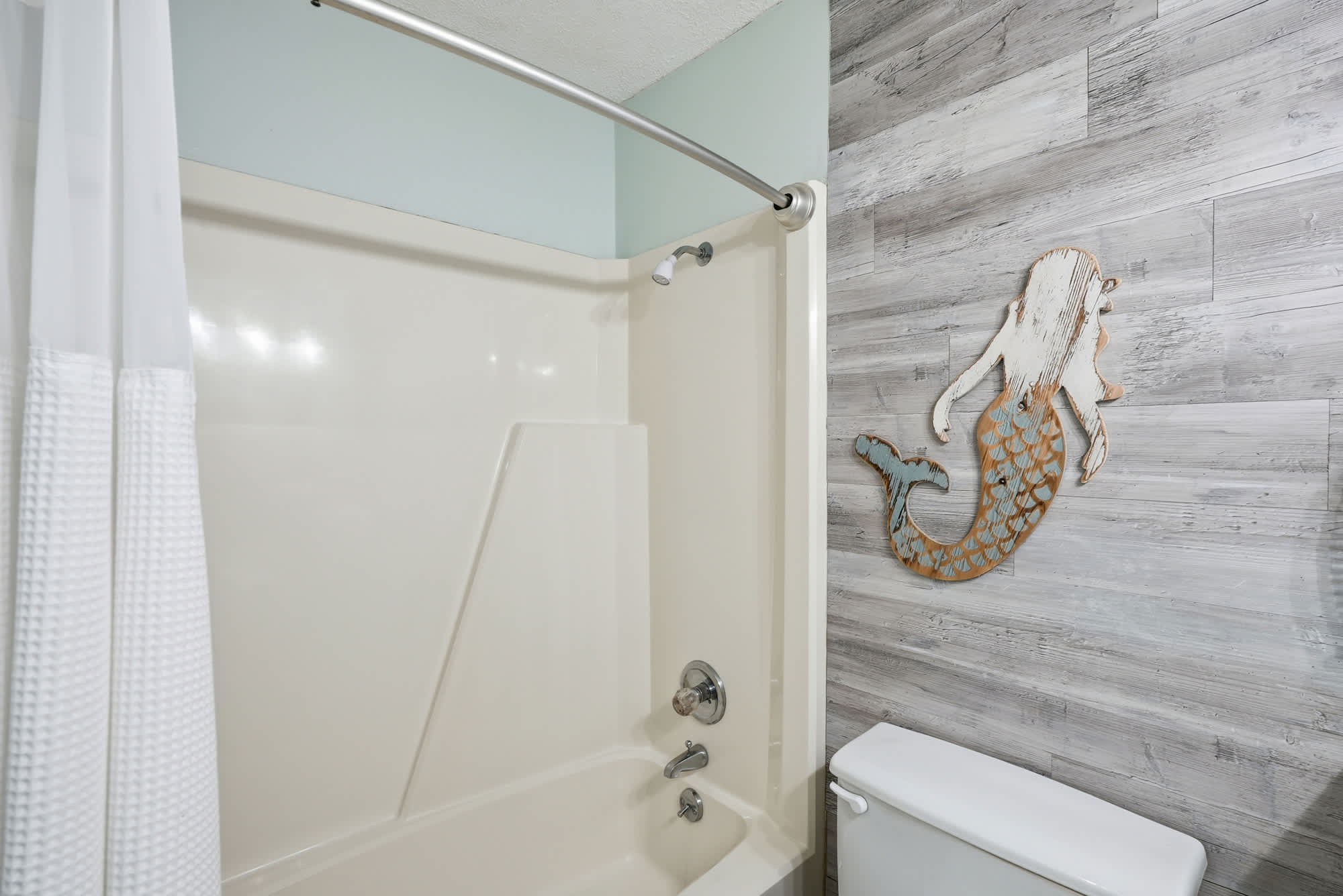 Top Of The Gulf  602 – Bathroom with a bathtub, shower curtain, decorated wall, and toilet.