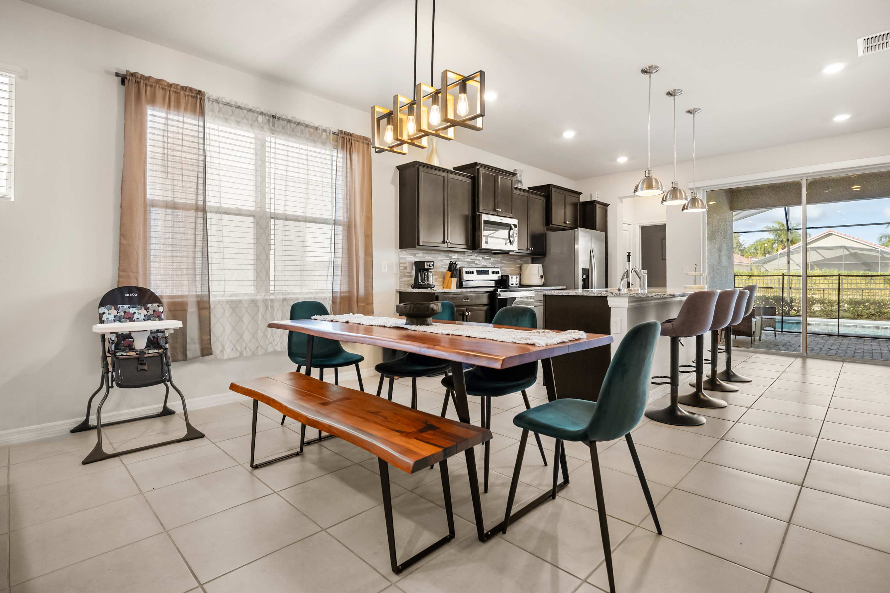 Spacious dining area with modern kitchen and pool view, perfect for family gatherings.