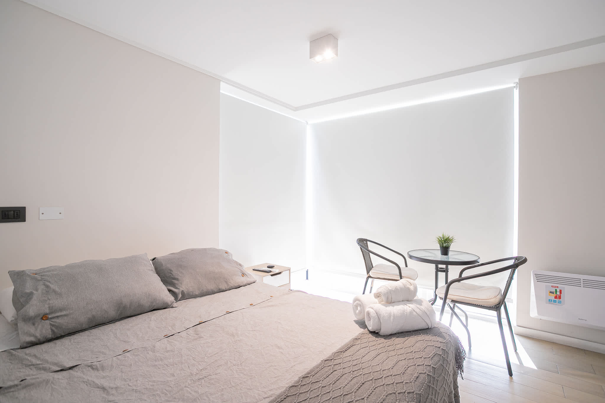 Cozy bedroom with modern decor and ample natural light, perfect for relaxation.