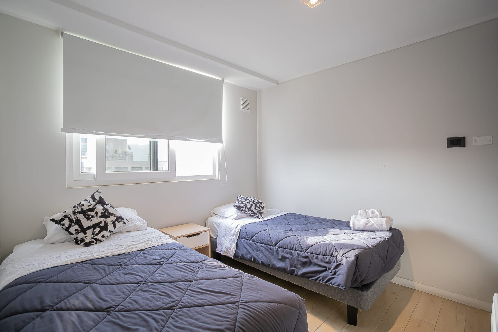 Cozy twin bedroom with ample natural light, perfect for a restful stay in the heart of the city.