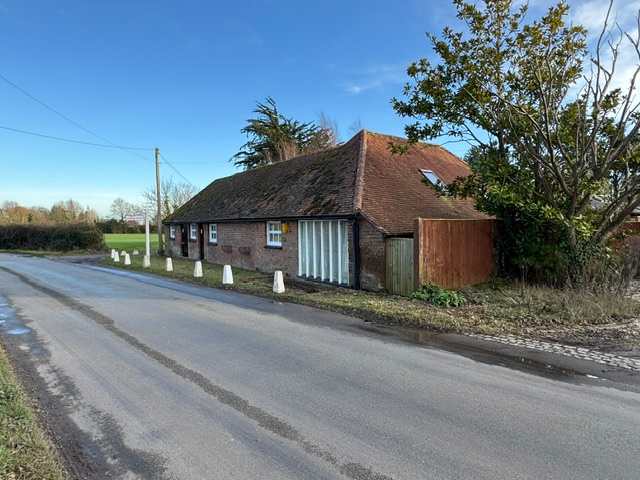 View of the Dairy and adjoining cottages from the road. The setting is rural and the road is relatively quiet, except for light traffic and farm vehicles.