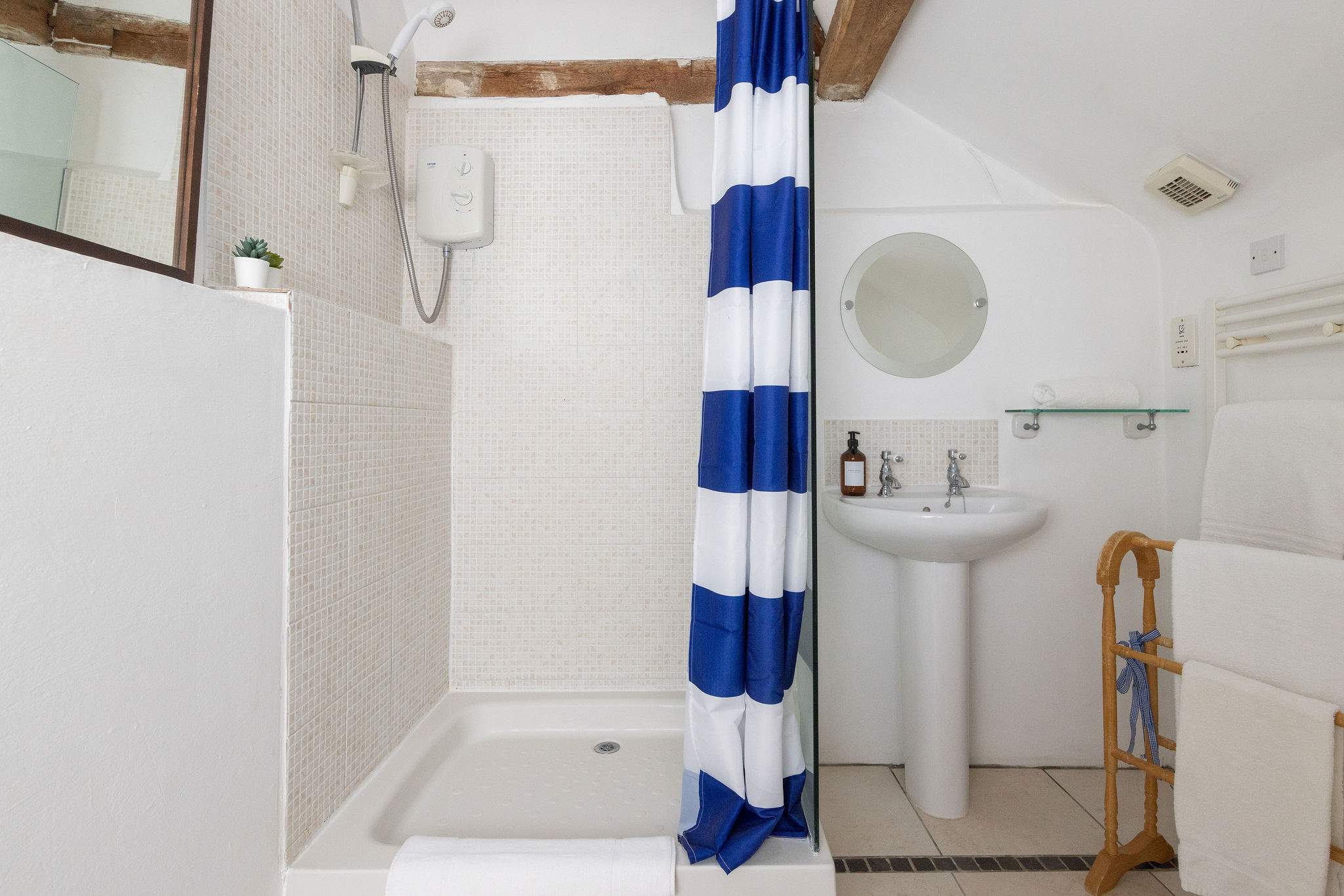 Clean and bright ensuite bathroom with shower, basin and essentials, such as fresh towels and toiletries.
