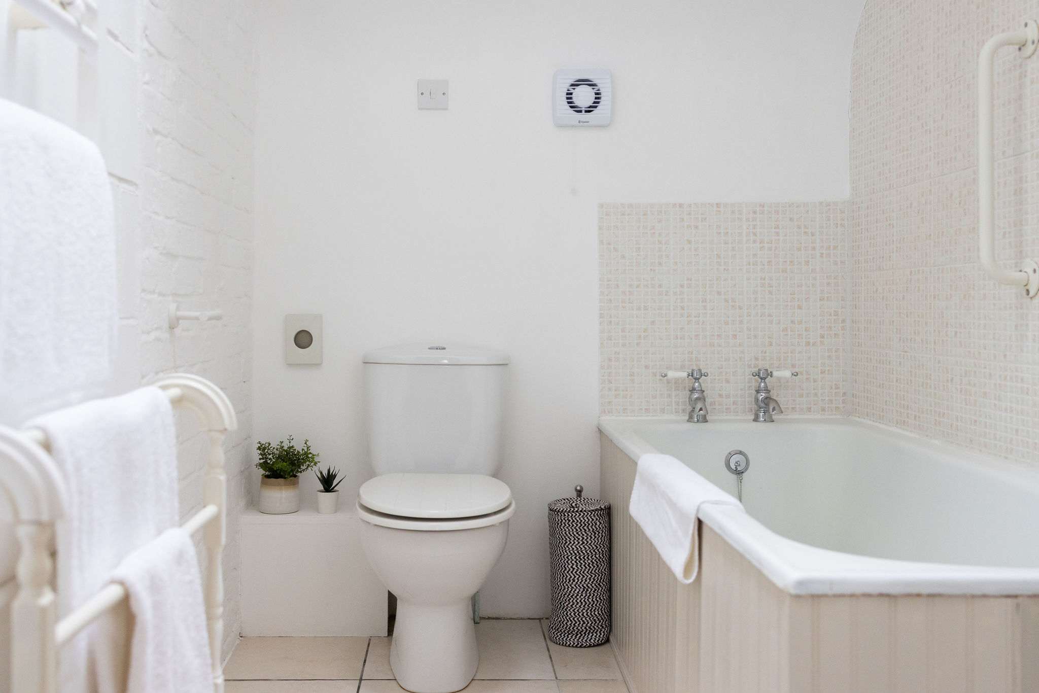Family bathroom with bath, overhead shower, and fresh towels, perfect for a relaxing soak after a day out.