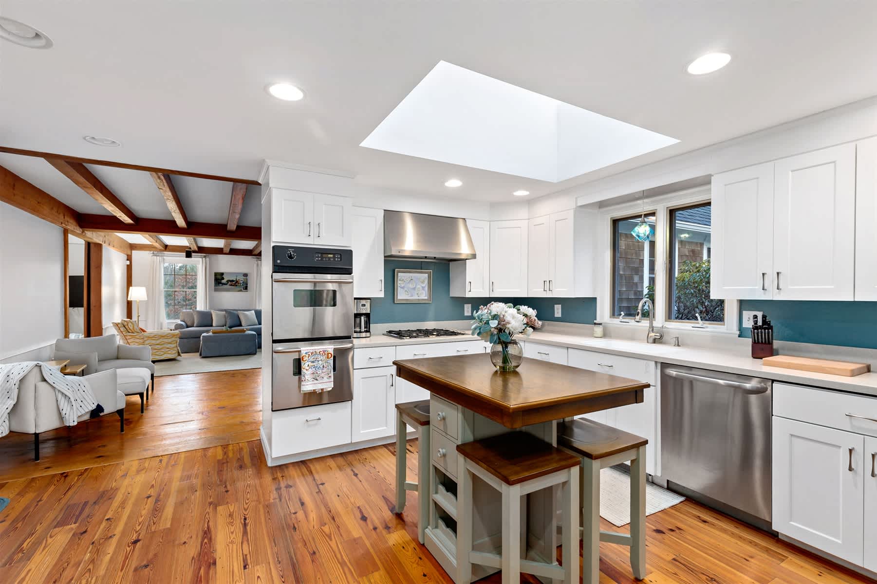 Updated white kitchen with skylight, stainless appliances, and island seating, perfect for quick breakfasts before exploring Orleans.