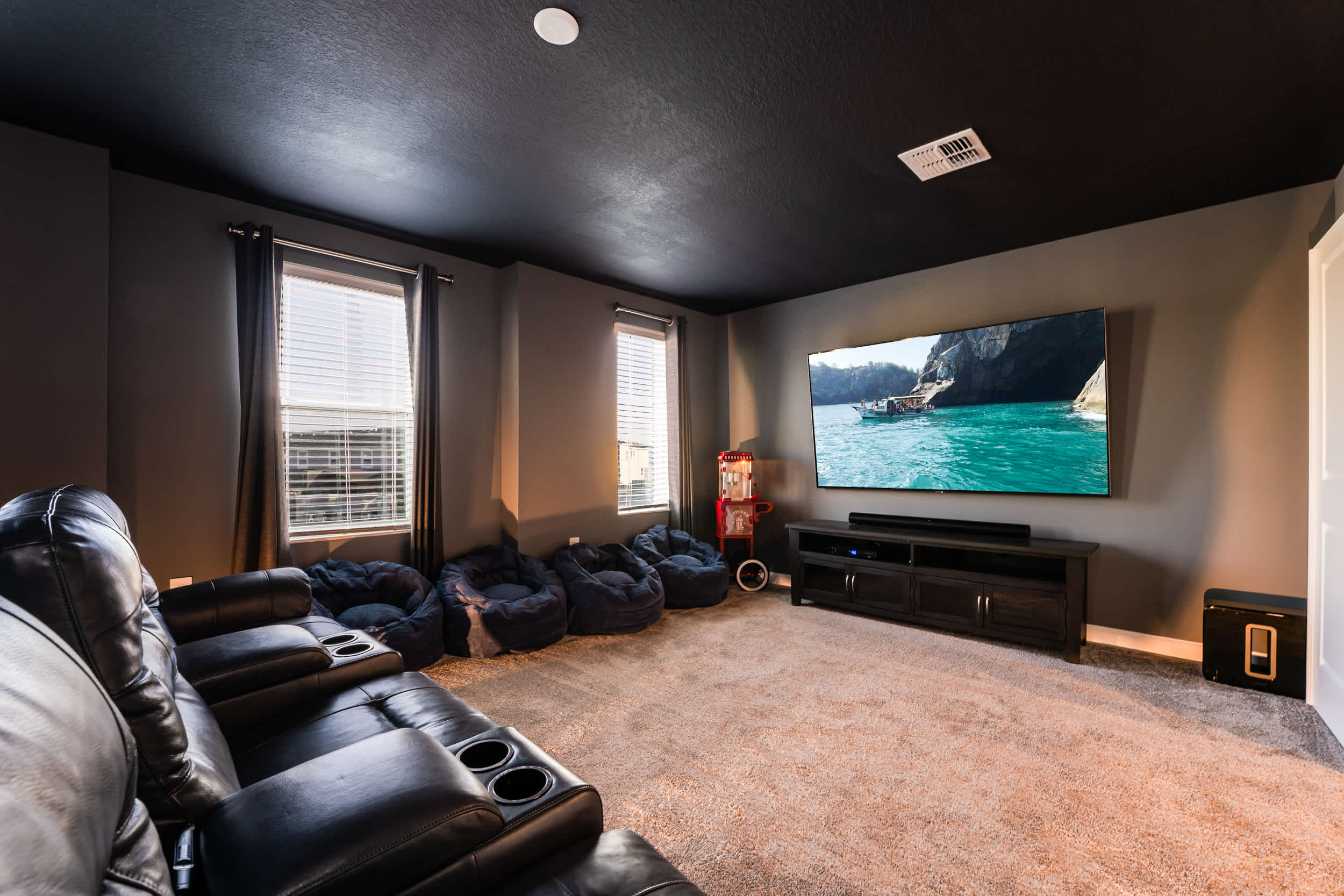 Experience ultimate relaxation in this private home theater with plush seating, a massive screen, and a popcorn machine for movie nights.
