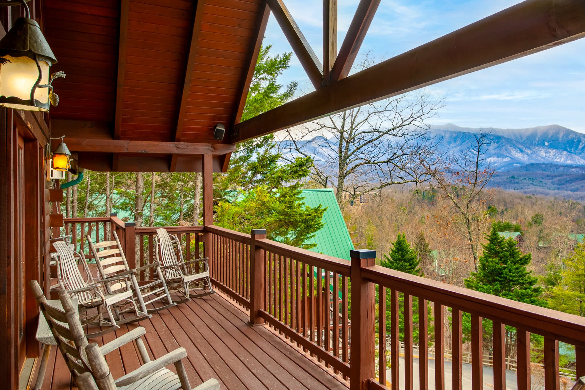 Relax on this expansive log cabin deck featuring rustic rocking chairs and stunning mountain views.