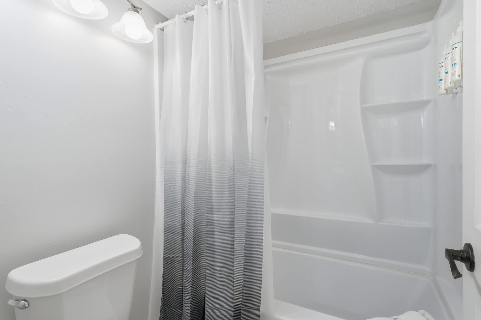 Dunes C104 – Bathroom featuring a toilet, bathtub, shower, and white curtains.