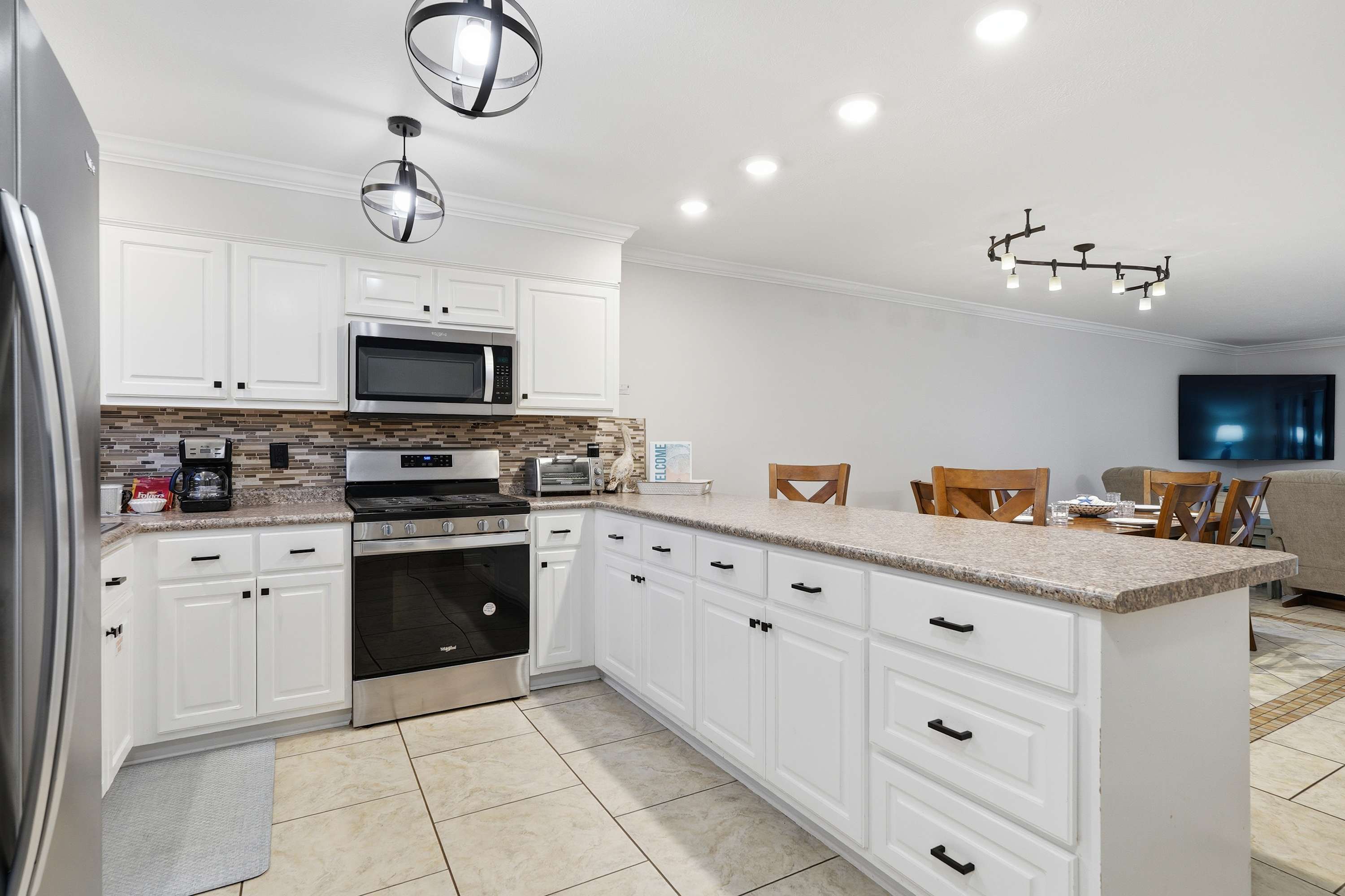 135 Grande Island Blvd – Modern kitchen with stainless steel appliances, granite countertops, and dining area in an open layout.