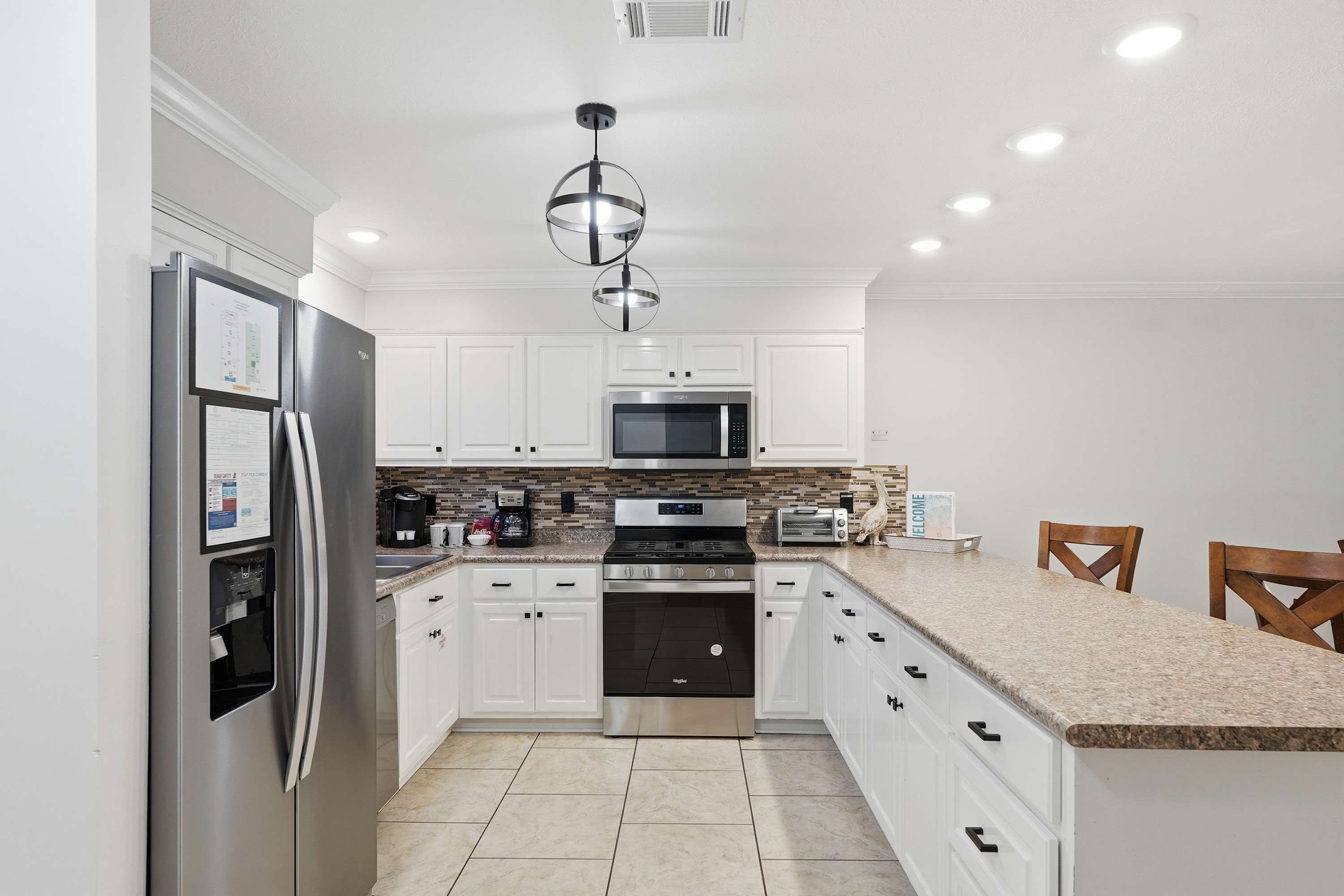 135 Grande Island Blvd – Modern kitchen with stainless steel appliances, granite countertops, white cabinetry, and seating area.